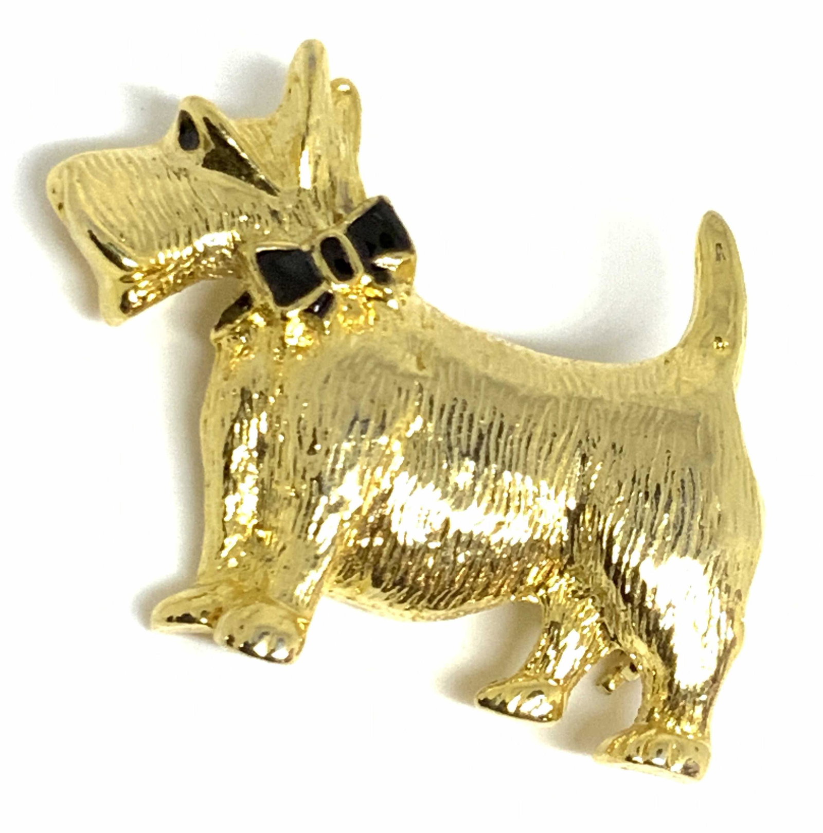 Vintage SCOTTISH TERRIER DOG Gold Tn Metal Brooch: A gold tone metal brooch in the form of a Scottish Terrier dog. The dog’s fur is etched to metal, which gives the brooch a more realistic quality. The dog sports a black enamel ribbon around it’s 