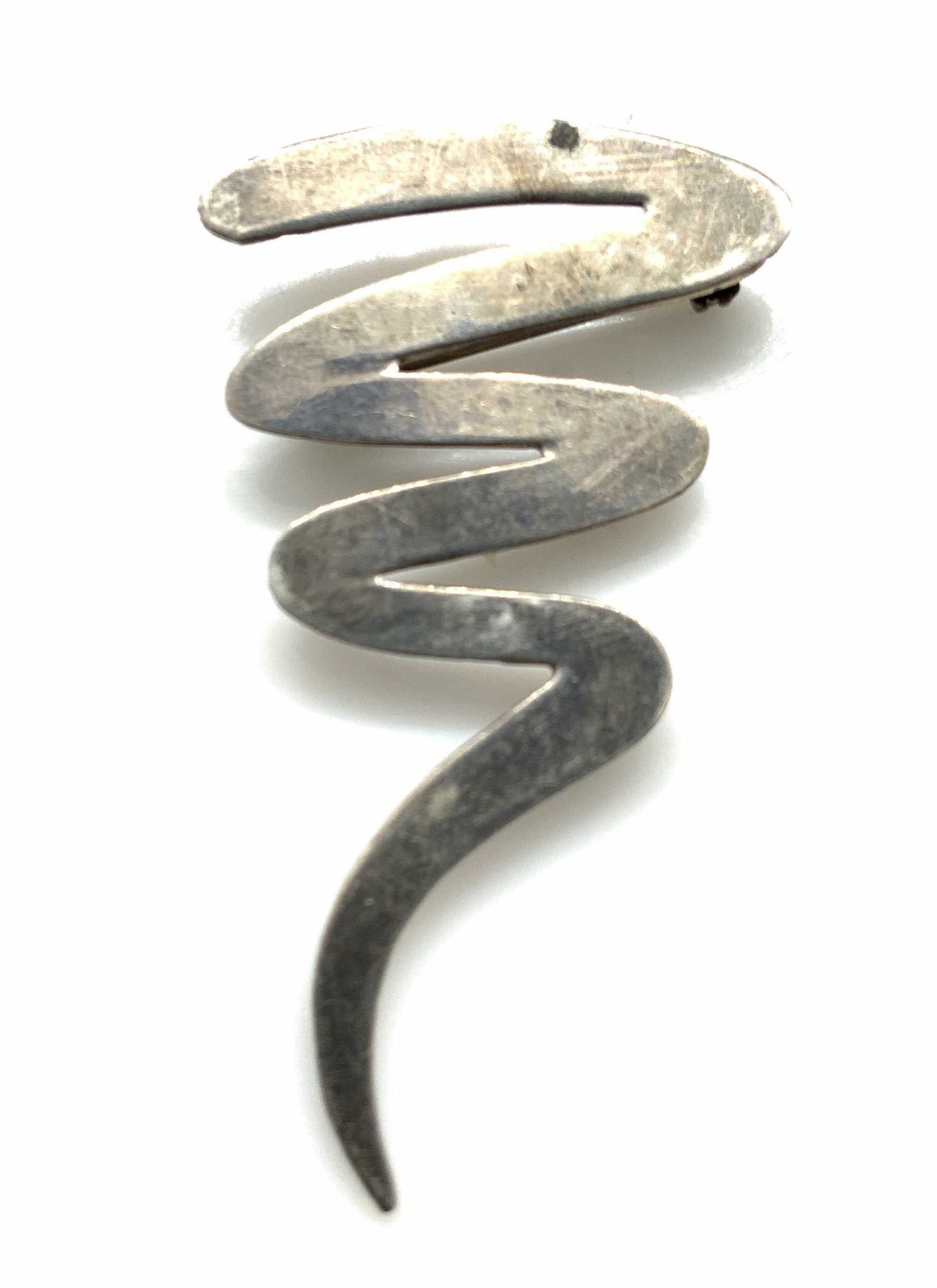Sterling Silver Brooch, Paloma Picasso Style: In the Style of Paloma Picasso, this is a Hallmarked squiggle brooch, marked 925 on verso. .15 ozt 2 x 1.25 in. Completed by pin stem and locking closure, c. 1980s Sterling silver squiggle brooch, Squ
