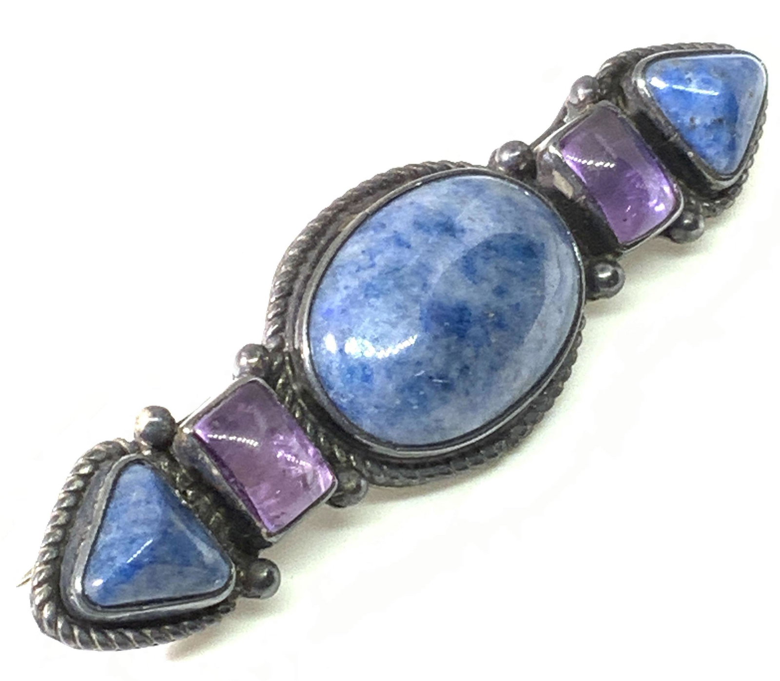 BEA TOM Sterling Silver Signed Natural Stone Pin: A vintage sterling silver artisan pin / brooch crafted by Navajo jewelry artist, Bea Tom. Amethyst and natural blue stone cabochons are bezel set upon the topside of this piece. The blue stone is spec