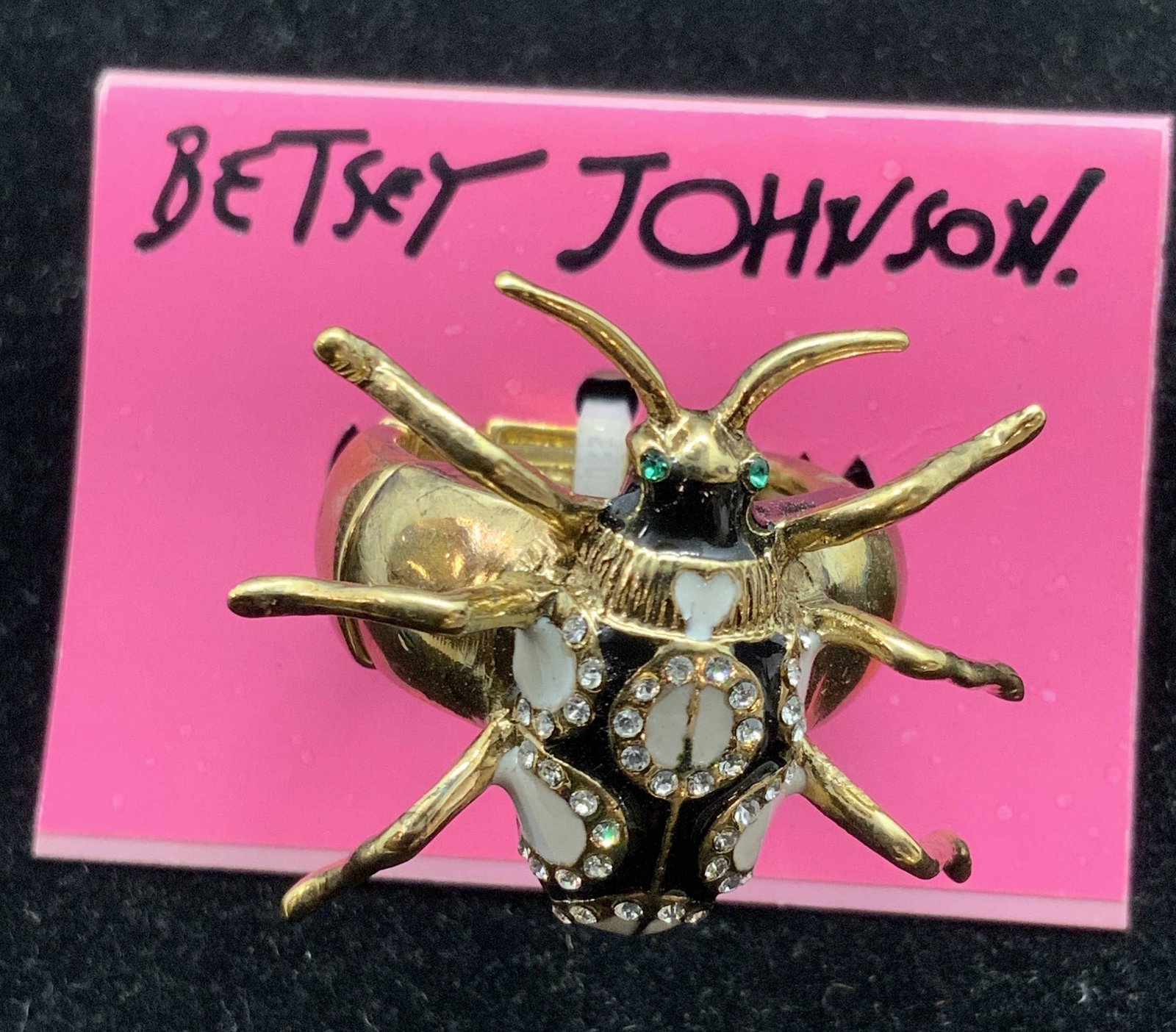 BETSY JOHNSON New W/ Tag Stretchy Insect Ring: A new, never worn, Betsy Johnson gold tone metal and enamel insect ring. The insect on the ring has six polished gold tone legs and two polished gold tone antenna. The body of the insect is decorated 