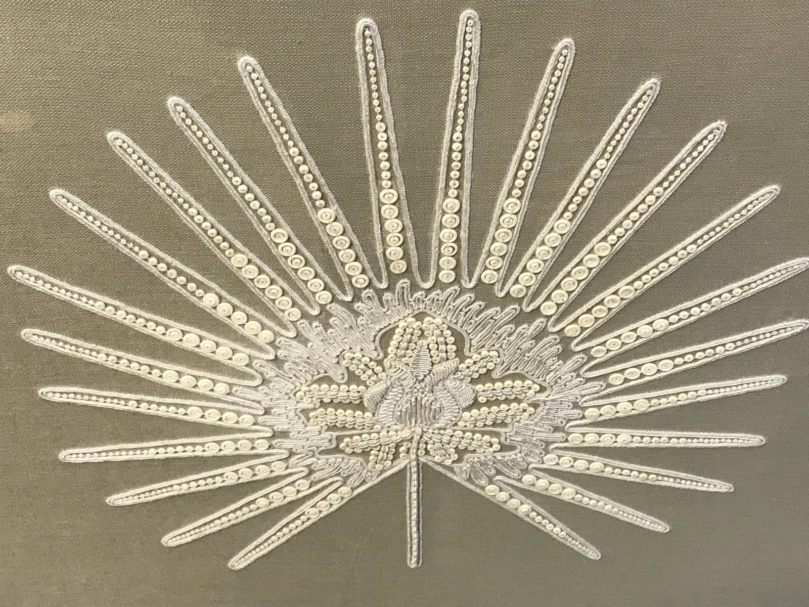 Mounted Embroidered Linen In Shadowbox: Mounted Embroidered Linen in shadowbox, label to reverse reads ‘Trowbridge’, subject a board of tan linen with white embroidery and beads in the shape of a leaf mounted on a board, white matting, 