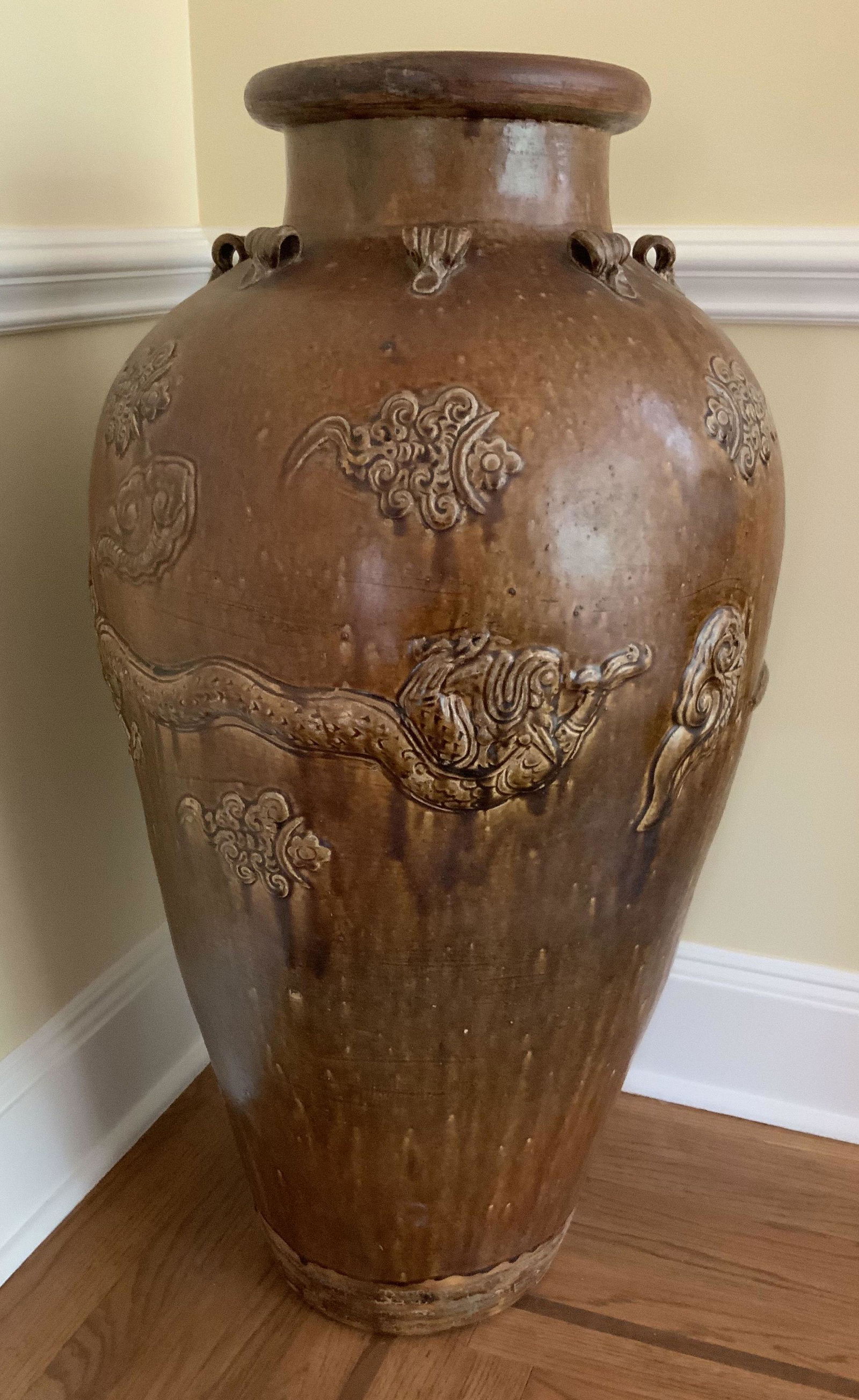 Floor Size Earth Toned Asian Glazed Ceramic Pot: floor size urn, vase, pot, decorative object, hand crafted with brown copper toned glazing, ballustrade shaped with curled handled detailing at neck, and raised design and pattern in relief, encirclin
