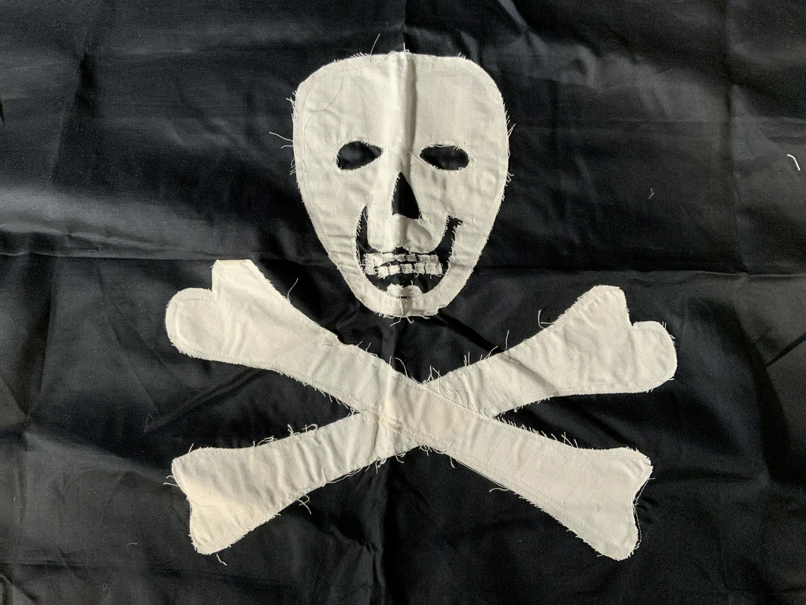 Hand Stitched Jolly Roger Flag: Hand Stitched Jolly Roger Flag, no apparent inscriptions or labels, skull and crossbones design, measures 26 3/4 x 38 3/8 inches, some frosting of fabric but overall in good condition, Hand stitched, 