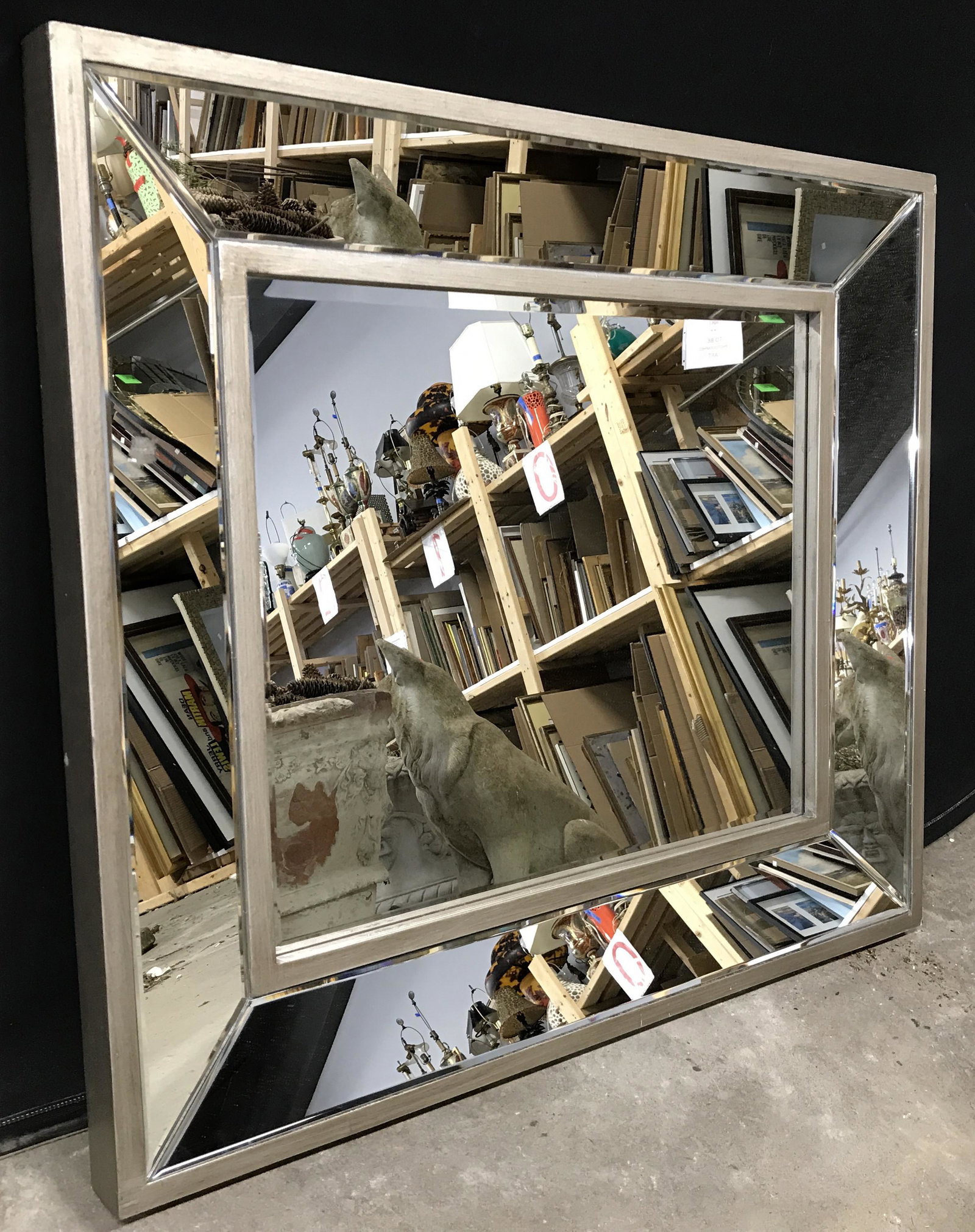 Multi Panel Beveled Wall Mirror: Wall mirror has silver toned frame which appears to be wooden. Center mirror surface is beveled. Mirror has multiple glass panels. Piece measures approximately 35 inches wide 32 inches deep. Piece can