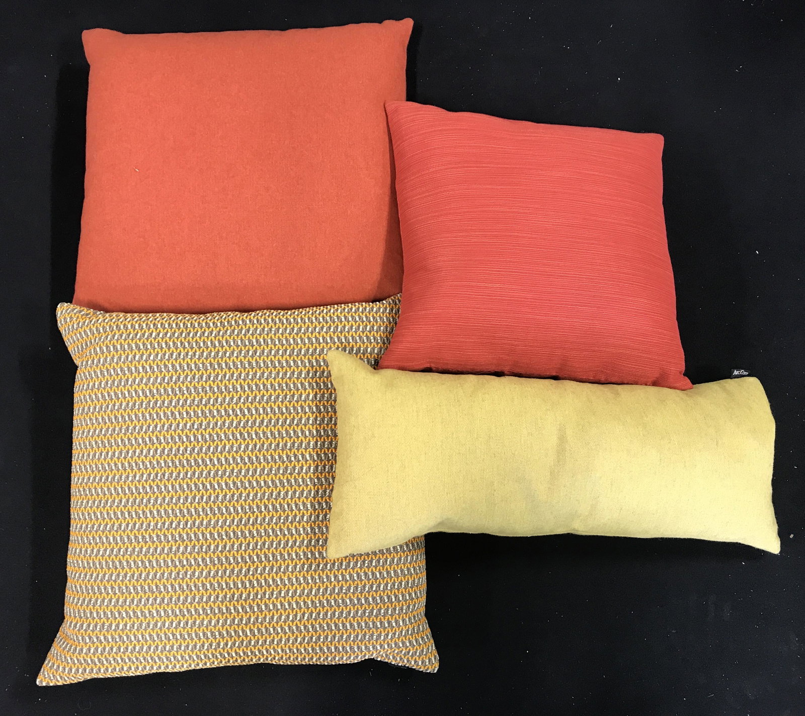 Lot 4 Throw Pillows Donated By ARC COM: Lot includes 4 pillows. Each have tag which reads ARC COM. Includes 1 yellow toned pillow 1 multi toned pillow, 1 red toned pillow & 1 orange toned pillow. Largest piece measures approximately 19 inch