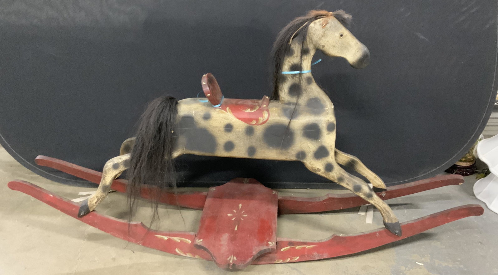 Vintage Hand Painted Wooden Rocking Horse: Hand painted rocking horse, crafted from wood. Piece is vintage, possibly antique. Horse is spotted, saddle is red. Underside reads as ORIGINAL DESIGN BY MARK SCHRUMPF, EXECUTED BY GARY HILL, 1st EDIT