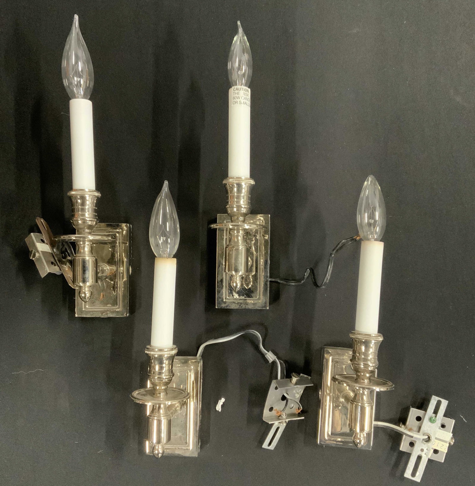 Set 4 Polished Metal Wall Sconces: Set of four wall sconces, polished metal finish. Each measures approx 12.5 inches H, and 2.5 inches W. Wear is consistent with use. Lighting, candelabra, chandelier, pendant light, chrome furnishings,