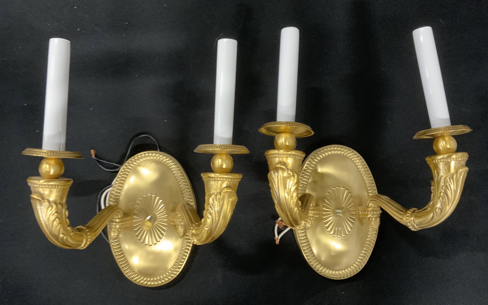 Pair Gilded Metal Wall Sconces: Pair of gilded metal wall sconces. Candle arms are possibly cast iron, base appears to be brass. Leaf like detailing is cast into each arm, each sconces houses two sockets. Each measures approx 12.25 