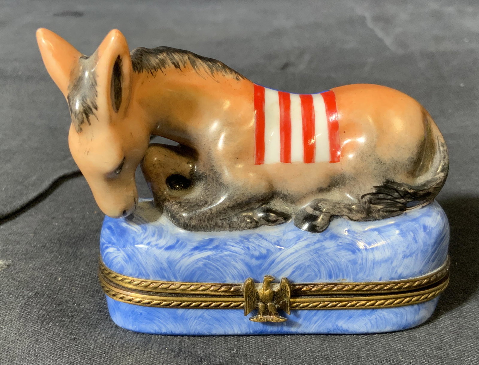 LIMOGES France Donkey Chamart Trinket Box: Donkey Camart Limoges France Trinket Box, underside of box reads ‘Chamart, Limoges, France, Peirt Main’, lid to box is a donkey with a flag draped atop its back, flag depicts 7 red and white alter