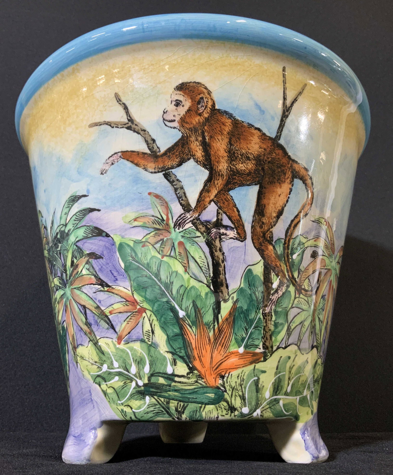MAXCERA Jungle Motif Porcelain Footed Cache Pot: Porcelain Cachepot with painted jungle scene. Monkeys, cheetahs, elephant, and foliage. Underside is signed: Maxcera, Made in China, Decorative Use Only, Not for Food Use. Underside also has some pitt