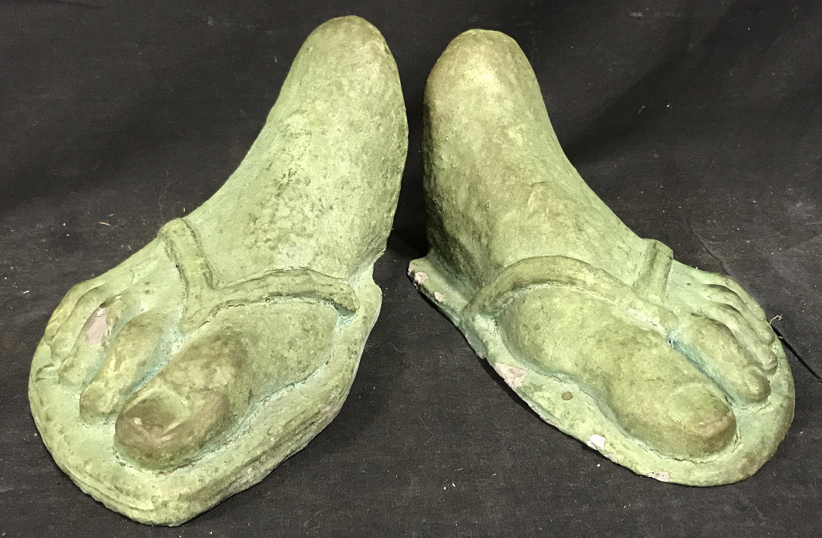 Grecian Sandal Book Ends: Grecian sandal book ends, made of possibly cement, Subject two feet paint Ed with a green patina wearing sandals, both measures approximately 9 inches long and 5.5 inches tall, chips to surface of bot