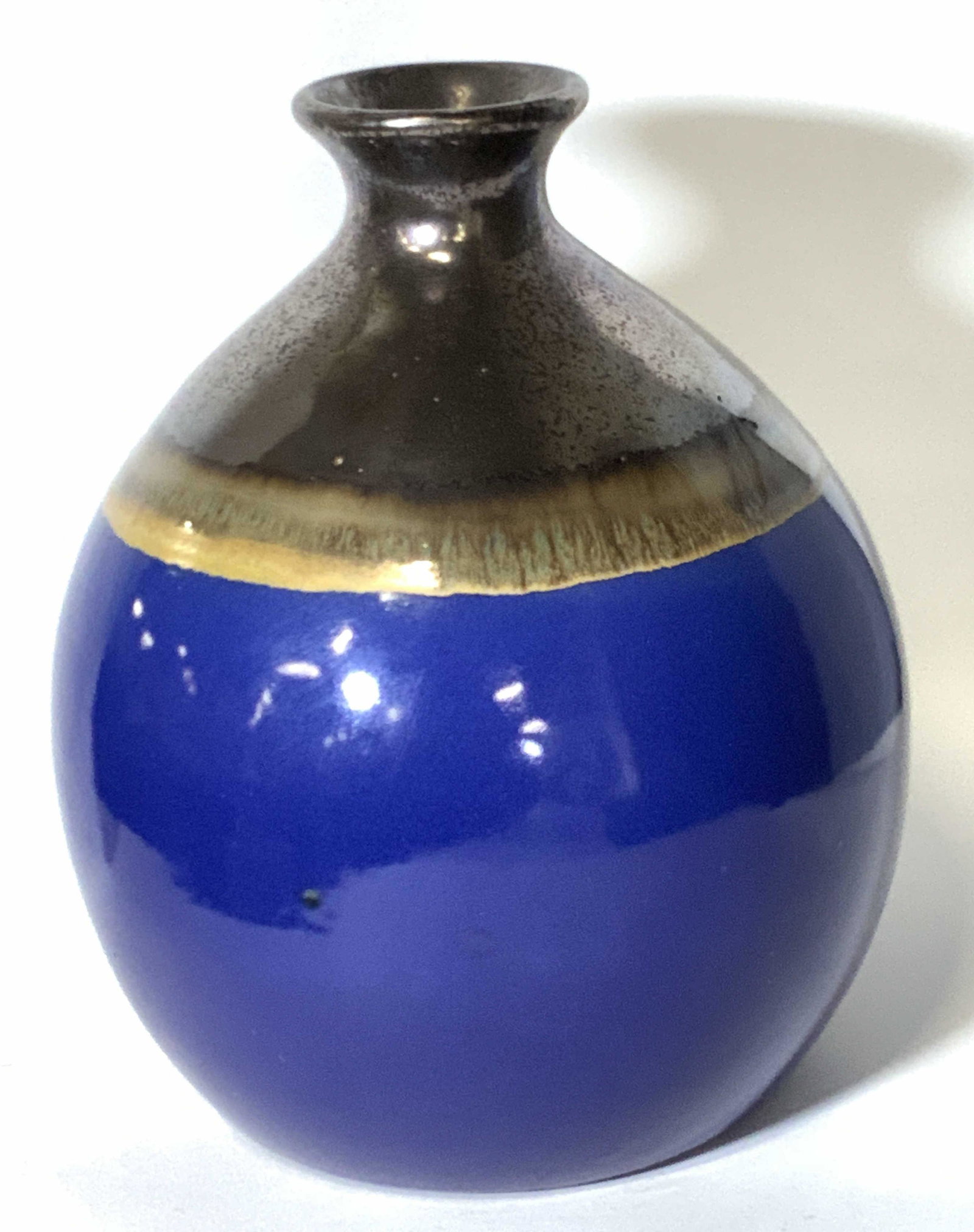 THREE HANDS Hand Painted Ceramic Jug Vase: A ceramic jug shaped vase hand painted and glazed. Coloring includes blue and brown hues. Along the top of the vase there is some pitting. Surface crack along the side of the vase, runs to underside. 