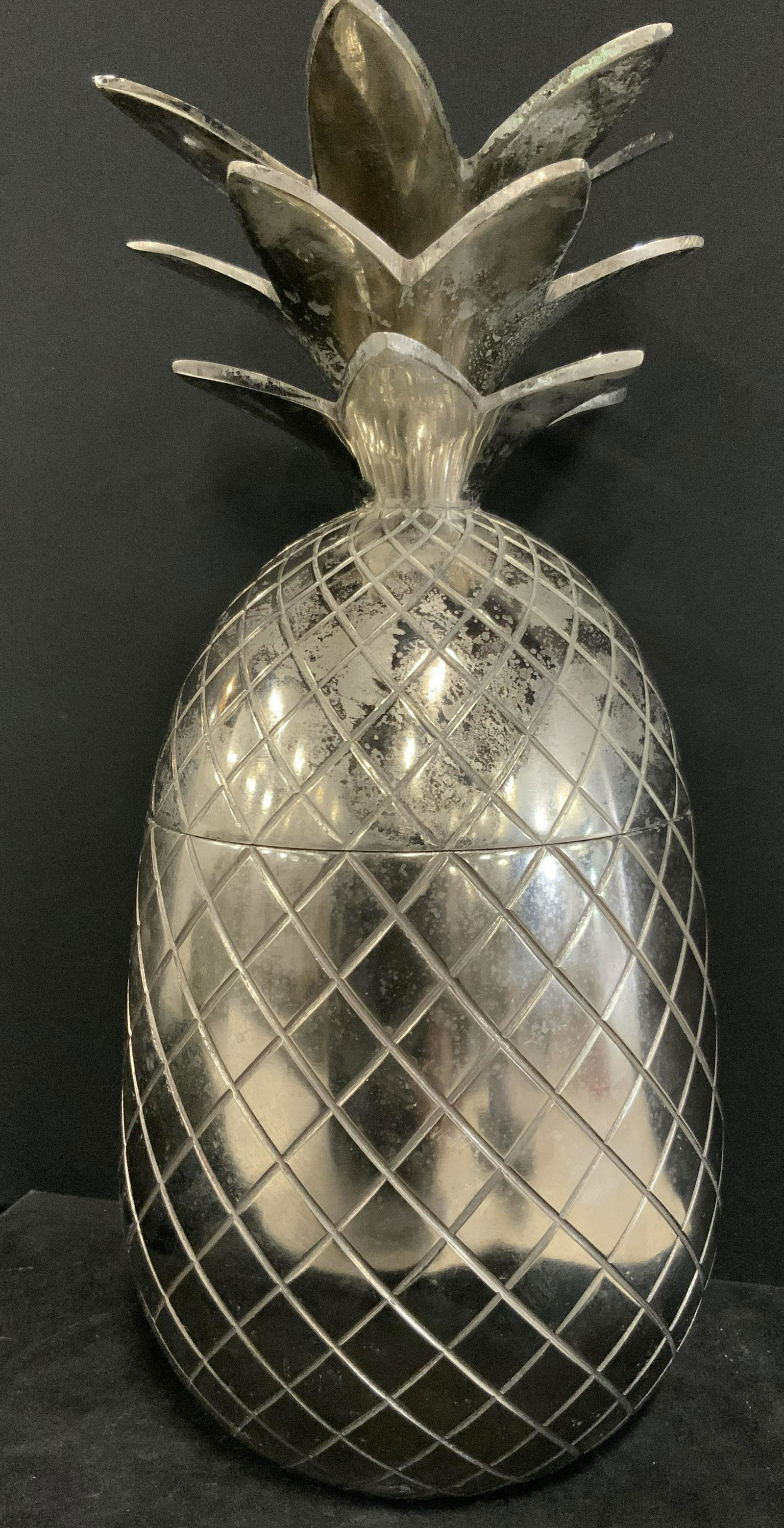TOMMY BAHAMA Lidded Metal Pineapple Ice Bucket: Polished silver tone metal pineapple form ice bucket / multipurpose vessel. Pineapple has etched designs mimicking the fruit’s natural form. The lid is the top part of the pineapple which features i