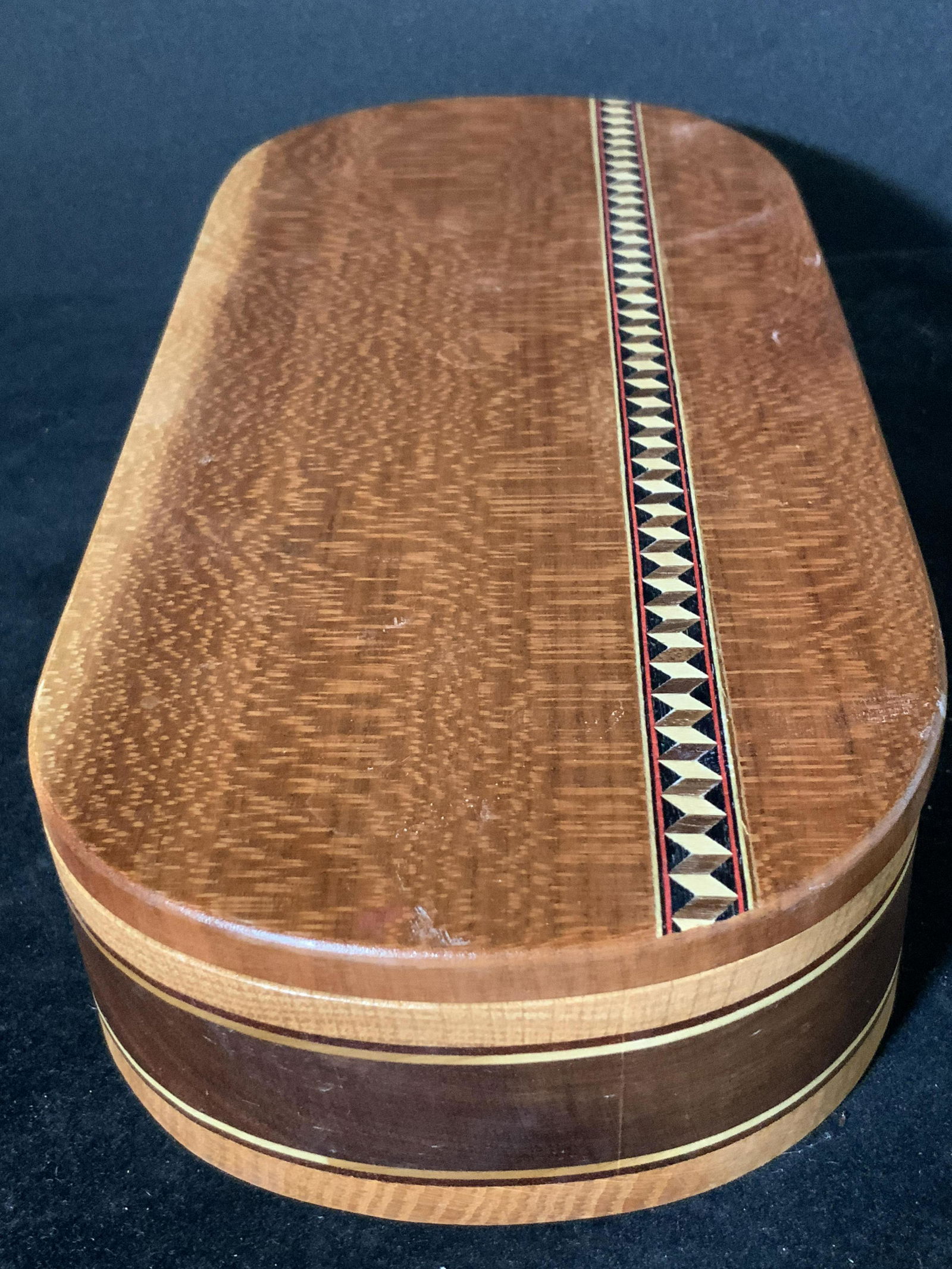 INGRID M JOCHIMSEN Handcrafted Wooden Keepsake Box: A hinged wooden trinket box handcrafted by Ingrid M. Jochimsen. The box has gold tone metal hardware that connects the lid to the base. The trinket box is made from a light colored wood. A decorative