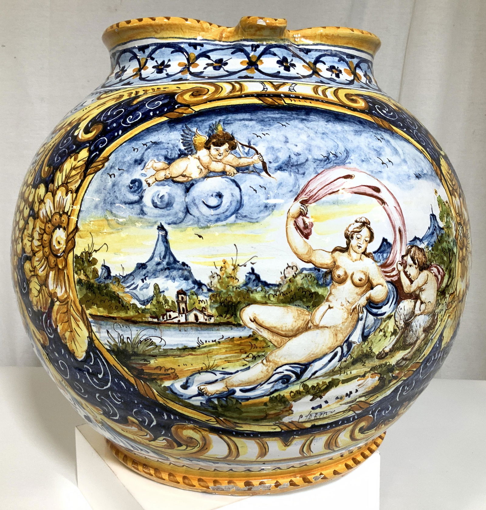 Signed European Cherub Deruta Style Pottery: Centerpiece ceramic orb jug, hand painted with blue florals on white. Central cartouche depicts mythical Angel cherub and half animal cherub in countryside with nude woman, hills and church in backgro