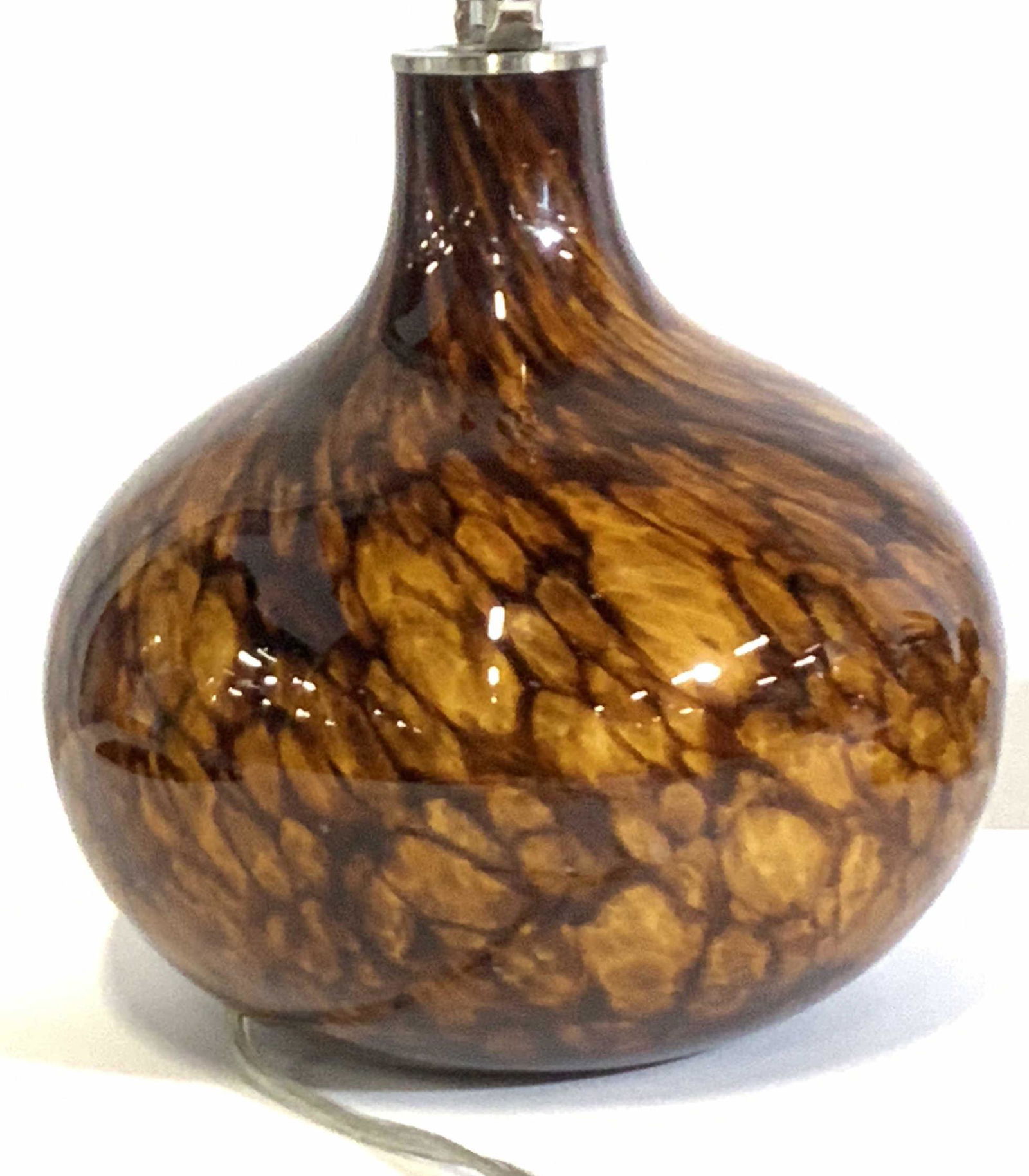 Hand Blown Rich Brown Art Glass Table Lamp: A bulb shaped glass tabletop lamp. Rich brown hues accented by gold tone shimmers throughout. Hues begin to swirl together towards the neck of the lamp. Circular brass toned finial accents the top. Tw