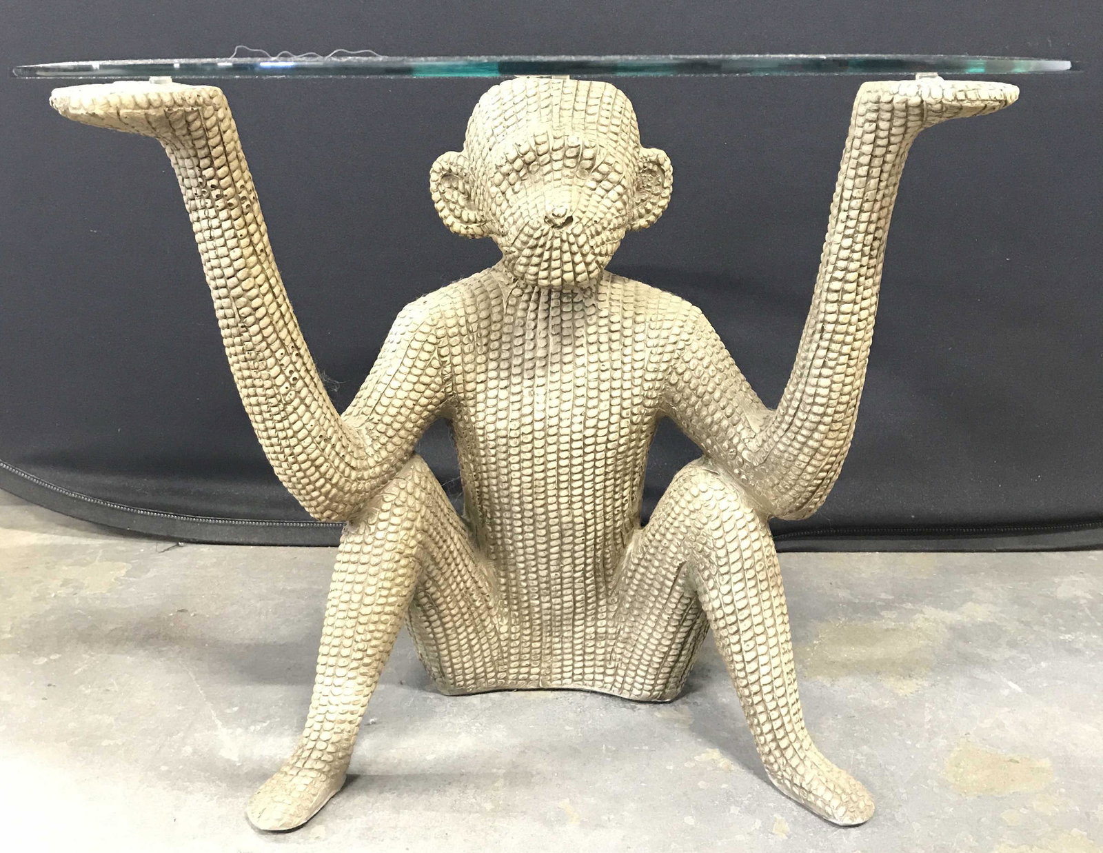 Monkey Base Glass Top Table: Table base is in the shape of a seated monkey. Base appears to possibly be wooden possibly composite. Tabletop is circular shaped and glass piece measures approximately 20 inches tall 24 inches wide. 