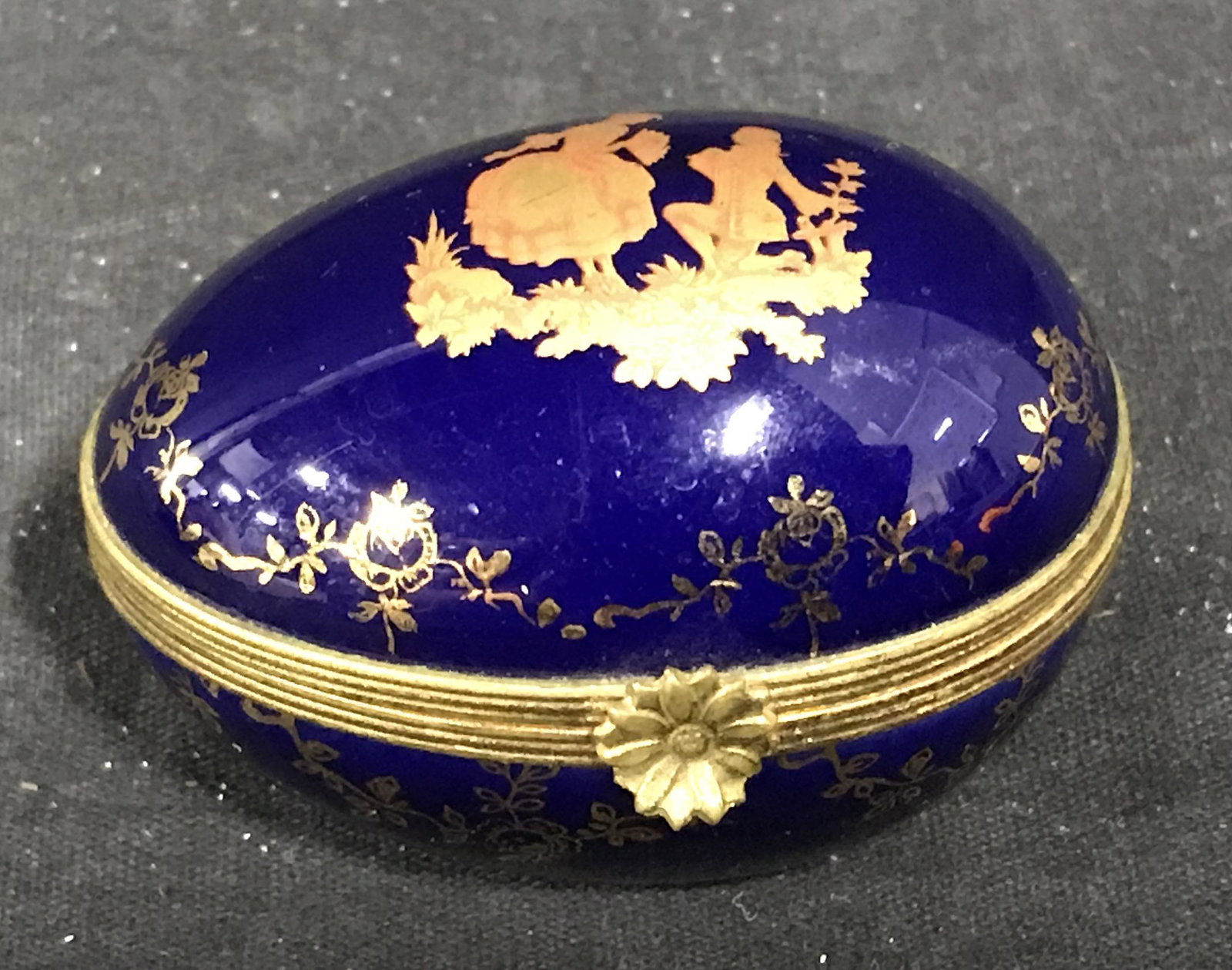 Limoges French Porcelain Egg Pill Box: Limoges French porcelain egg jewelry box, gold toned metal accents, painted royal blue with gold designs, label to underside reads ‘Limoges, Limoges Made in France’, floral gold tones metal clasp 
