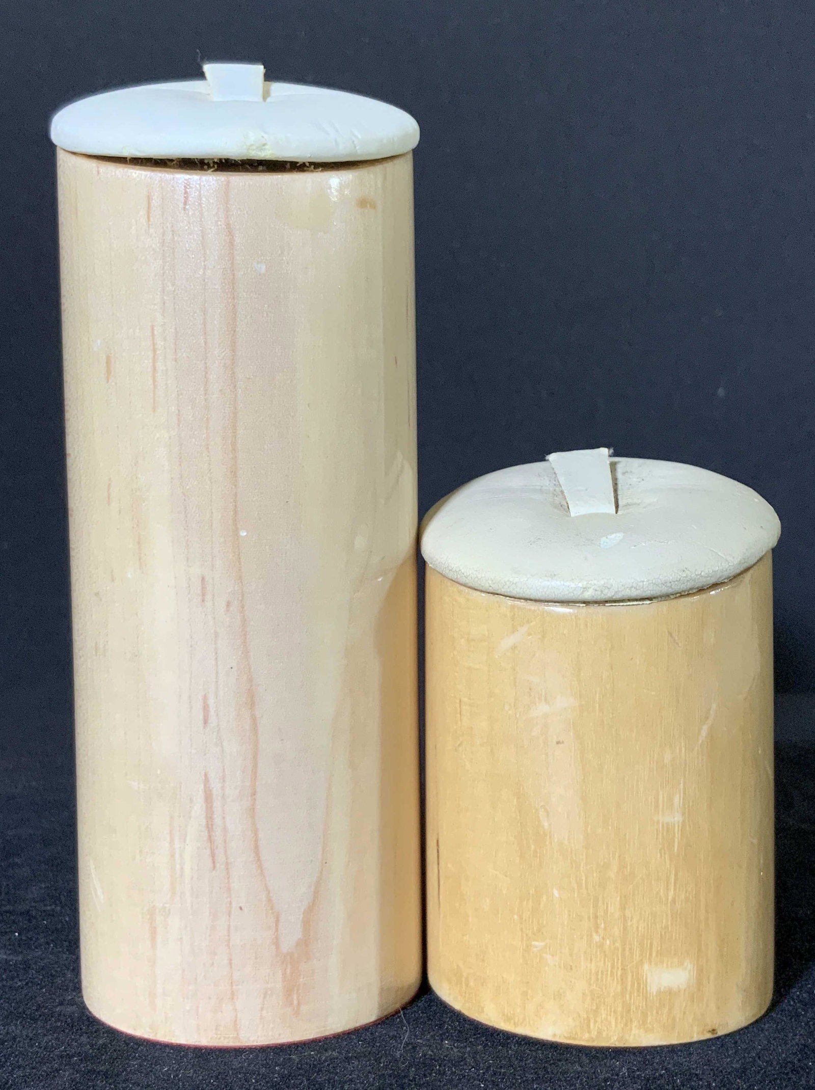 Pair Wooden Tabletop Ornaments: A pair of wooden tabletop ornaments. One is taller than the other. Wooden base with red felt on underside. Topper is a white, cushioned fabric. Could be used to display jewelry, bracelets, bangles, an