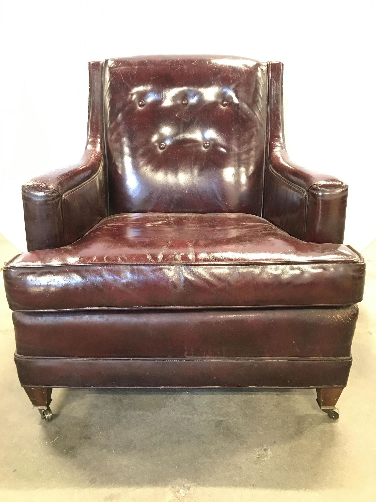 W&J SLOANE Leather Upholstered Armchair On Casters: Tag reads W&J SLOANE. Chair is mahogany toned, upholstered in leather and has tufted backrest. Front 2 feet have gold toned brass casters. Armchair, w&j sloane armchair, leather armchair, armchair on