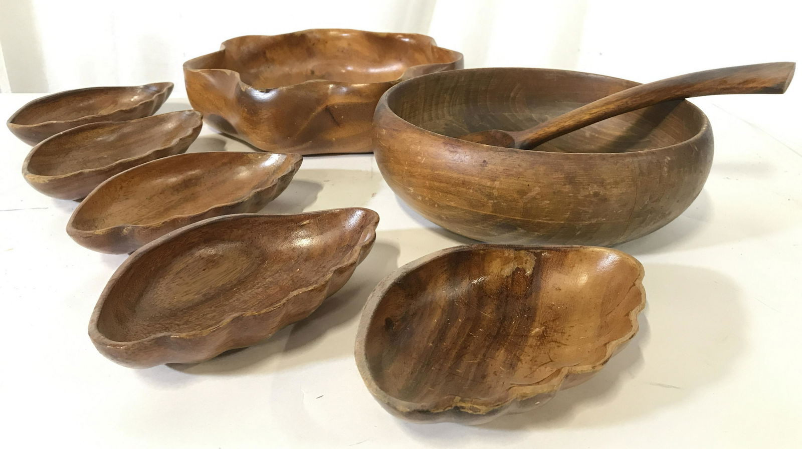 Lot 8 Vintage Teak Serveware: Lot includes 5 shell shaped dishes, 2 serving bowls, & 1 spoon. Each piece is teakwood. Largest piece measures approximately 12 inches wide 3 inches tall. Serveware, teak, monkey pod, teak dishes, tea