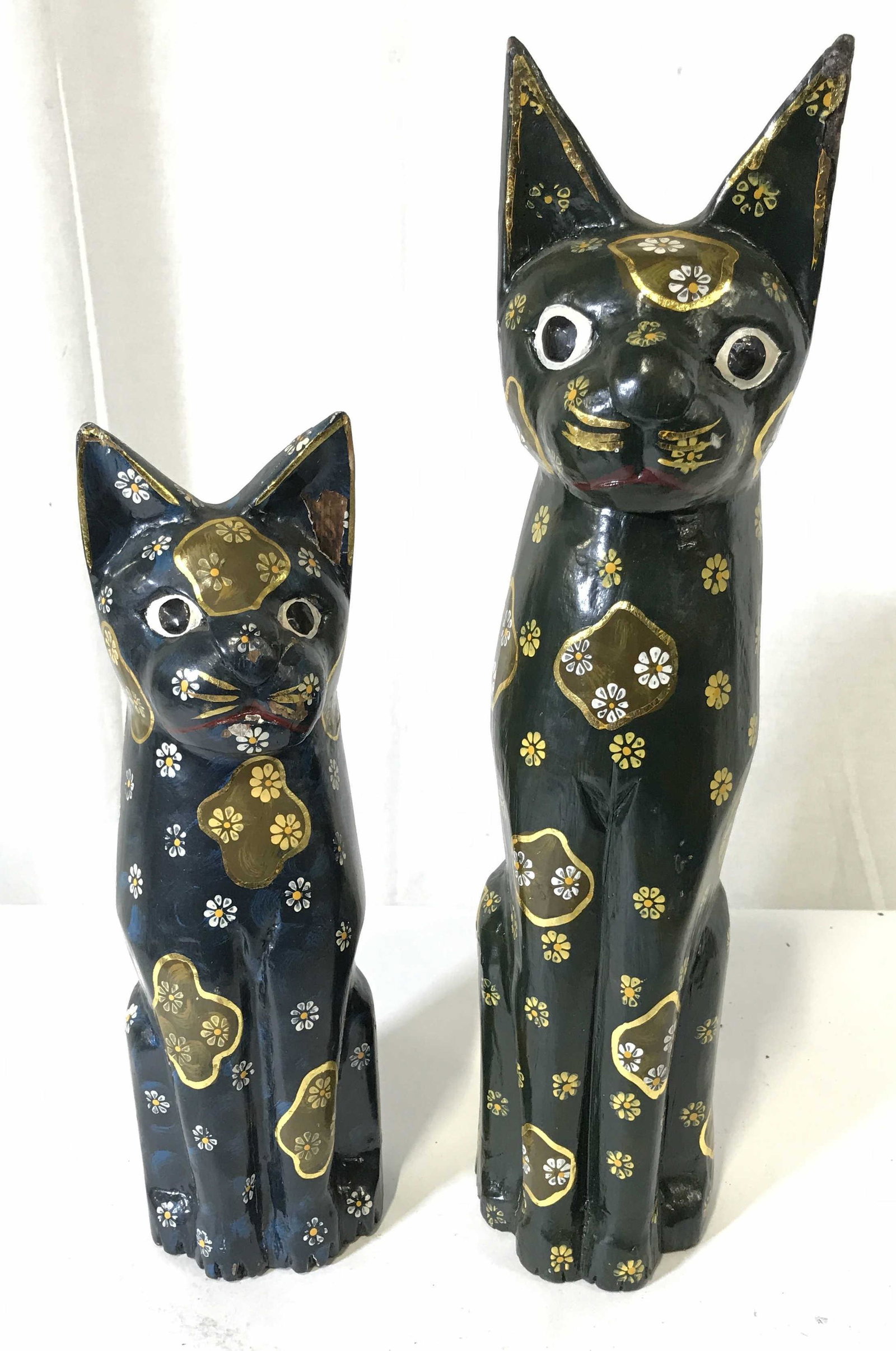 Pair Indonesian Wooden Cat Statues: Pair Indonesian wooden cat statues, label to underside of both read ‘Made in Indonesia’, subject two wooden cats hand painted blue and green with floral designs, tallest one measures 15.5 inches t