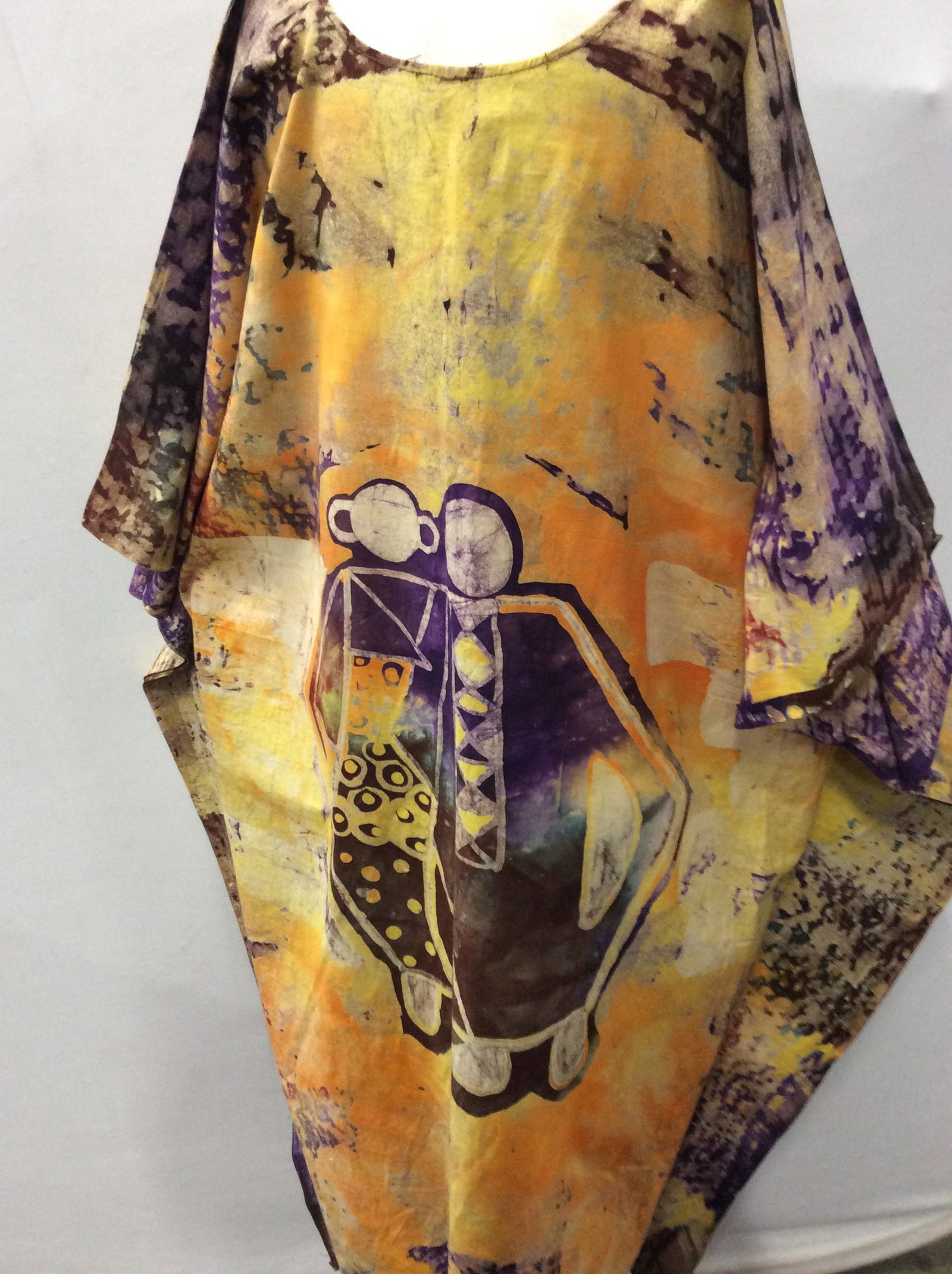 Tribal Print Batik Caftan, unisex: Long caftan with tribal print, heavier cotton batik, mostly yellow- orange with purple and red abstract designs. Scoop neck, 52 in long. Loose fitting 30 in. Across to fit body. Possibly created Out o