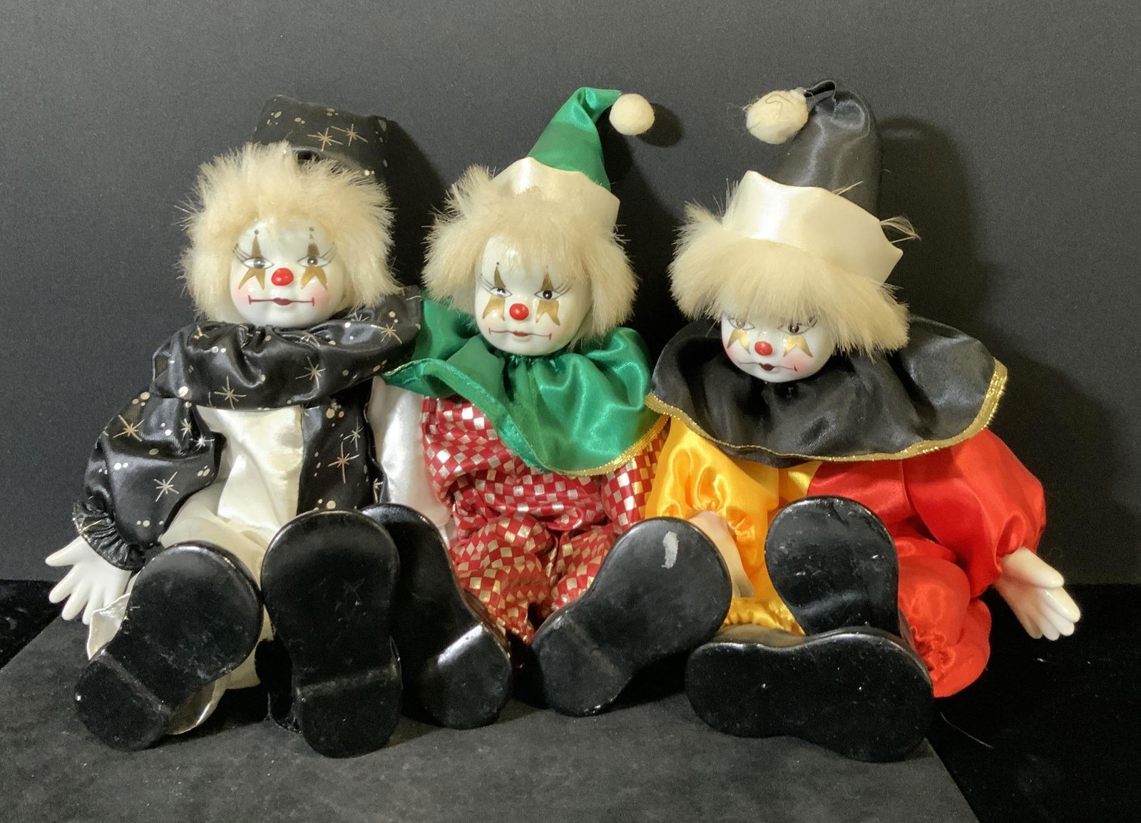 Set 3 Hand Painted Porcelain Circus Clown Dolls: White porcelain hands and faces. Hand painted with stars around eyes, red button nose, plump lips and long eyelashes. Oversized painted black porcelain clown shoes. Clowns dressed in traditional circu