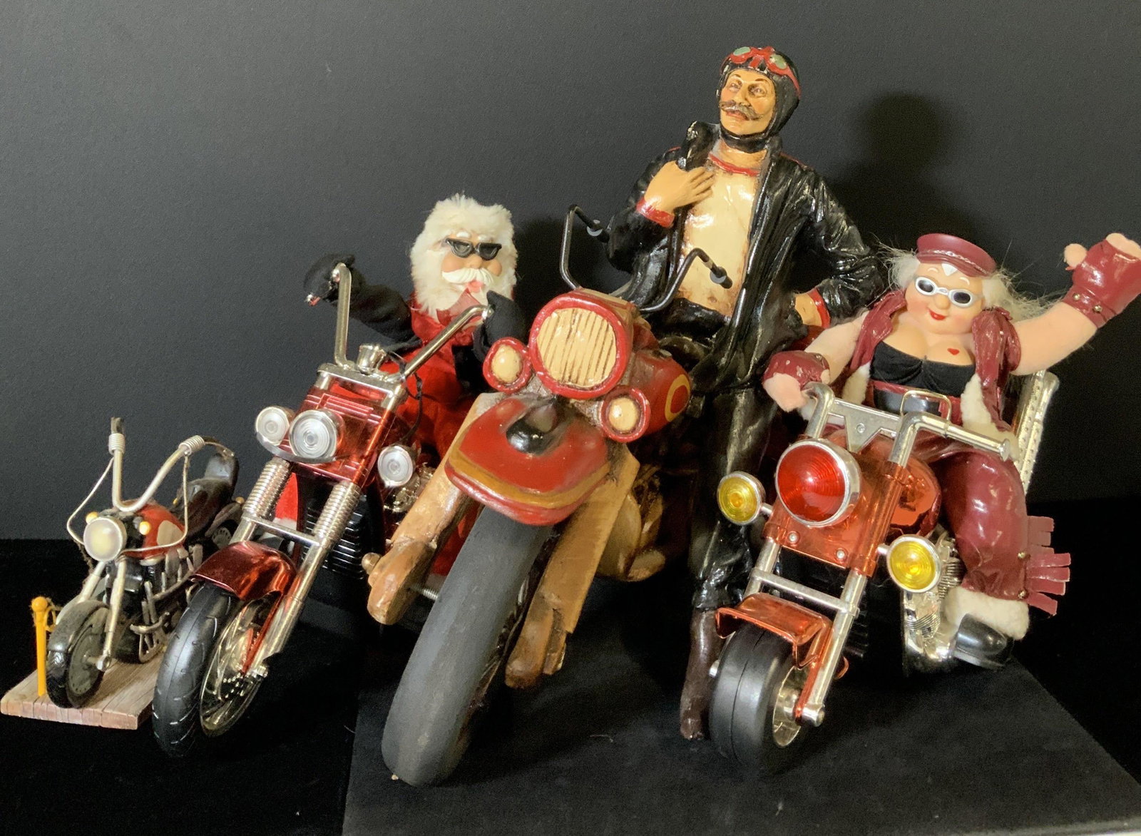 Lot 4 Tabletop Standing Motorcyclist Figurals: Four motorcycles, three with riders, one stand alone. All four motorcycles stand on their own. One motorcycle features a Santa Claus figural with sunglasses riding atop. The Santa has a button to acti