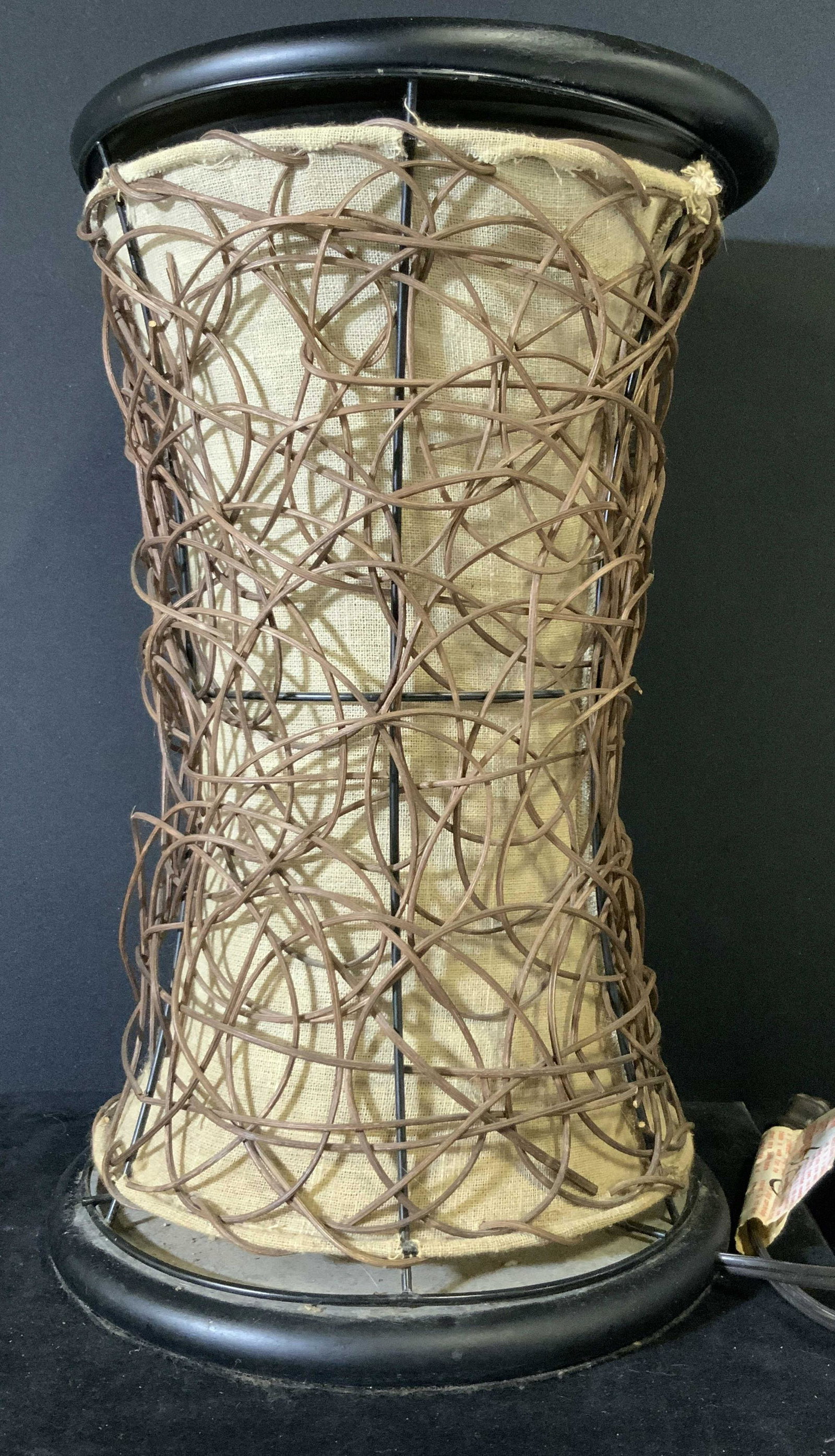 Tanglewood & Fabric Tabletop Lighting Fixture: A tabletop lamp that has fabric and tanglewood accents. The tanglewood is a deep brown color. The fabric is a light beige. The top and base are both black. The top is removable and reveals the lightbu