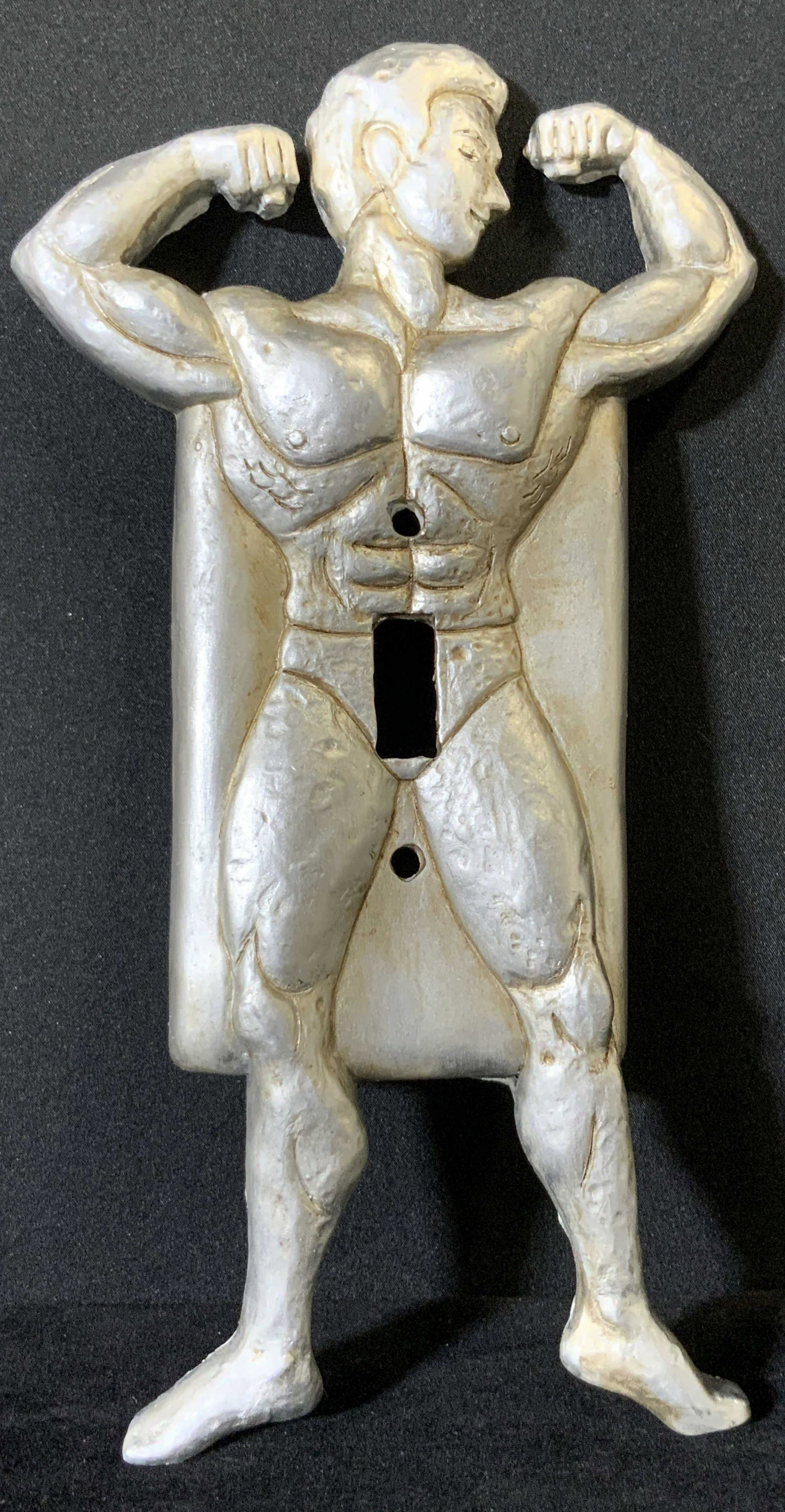 Set 6 Silver Tone Strong Man Light Switch Covers: Six composite light switch covers that are in the form of strong men flexing. The pieces are silver toned and have etched details throughout the male form. The men depicted are buff, having abs and la