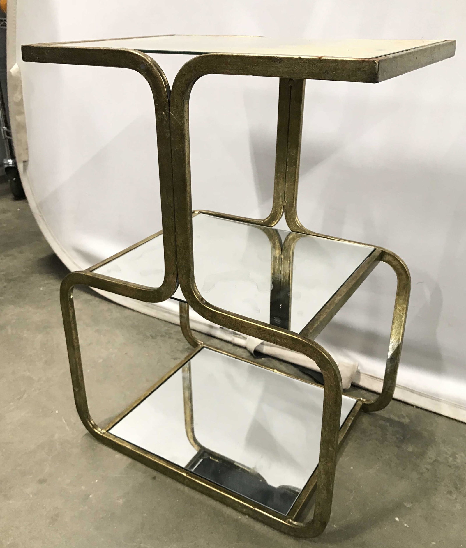 Metal Mirror Top Side Table: Side table frame is gold toned and metal. Possibly gold leafed. Piece has mirrored top, middle shelf and base area. Piece measures approximately 25 inches tall 18 inches wide wide 13 inches deep. Side