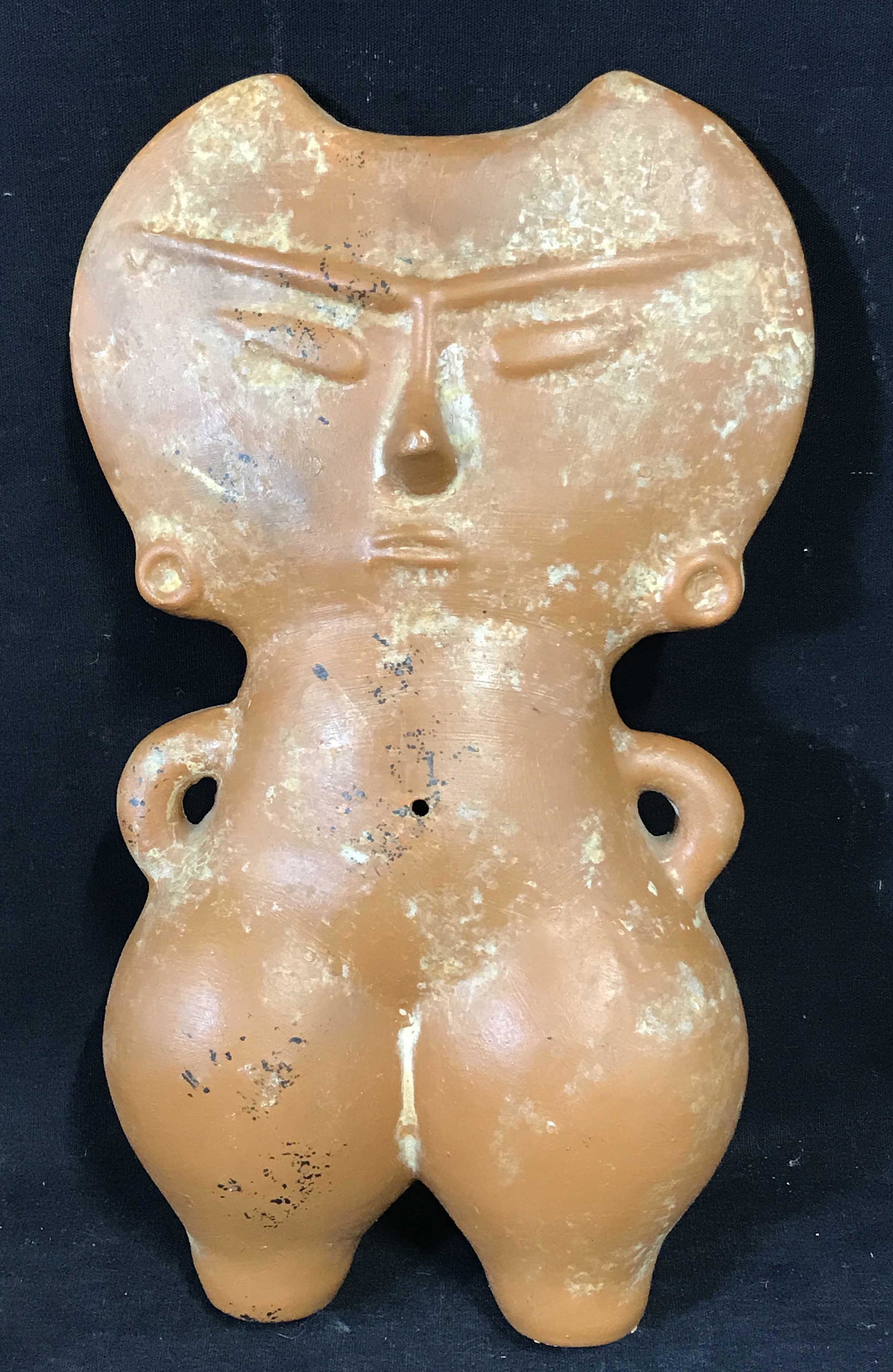 Orange Painted Ceramic Primitive Figure: Orange painted ceramic primitive figure, subject a primitive looking figure with a double axe shaped head a small torso with handles for arms and puffy pant legs, measures 12 inches at tallest point, 