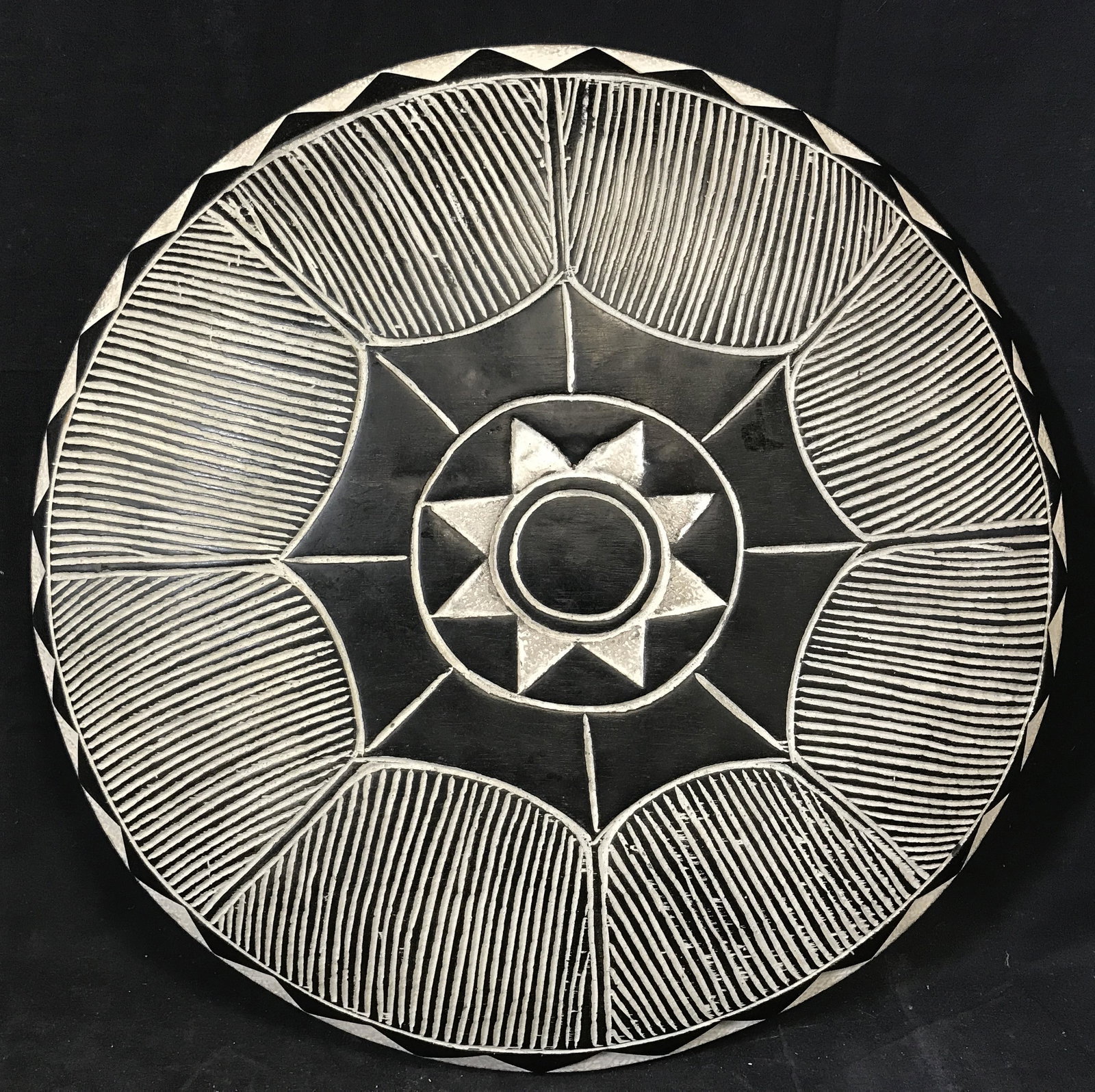 Traditional South African Tribal Shield: Ceremonial Zulu Shield, origins can be found in South Africa, wooden shield with black and white paint with a sun pattern carved into the front, handle carved into the back, diameter approximately 21 