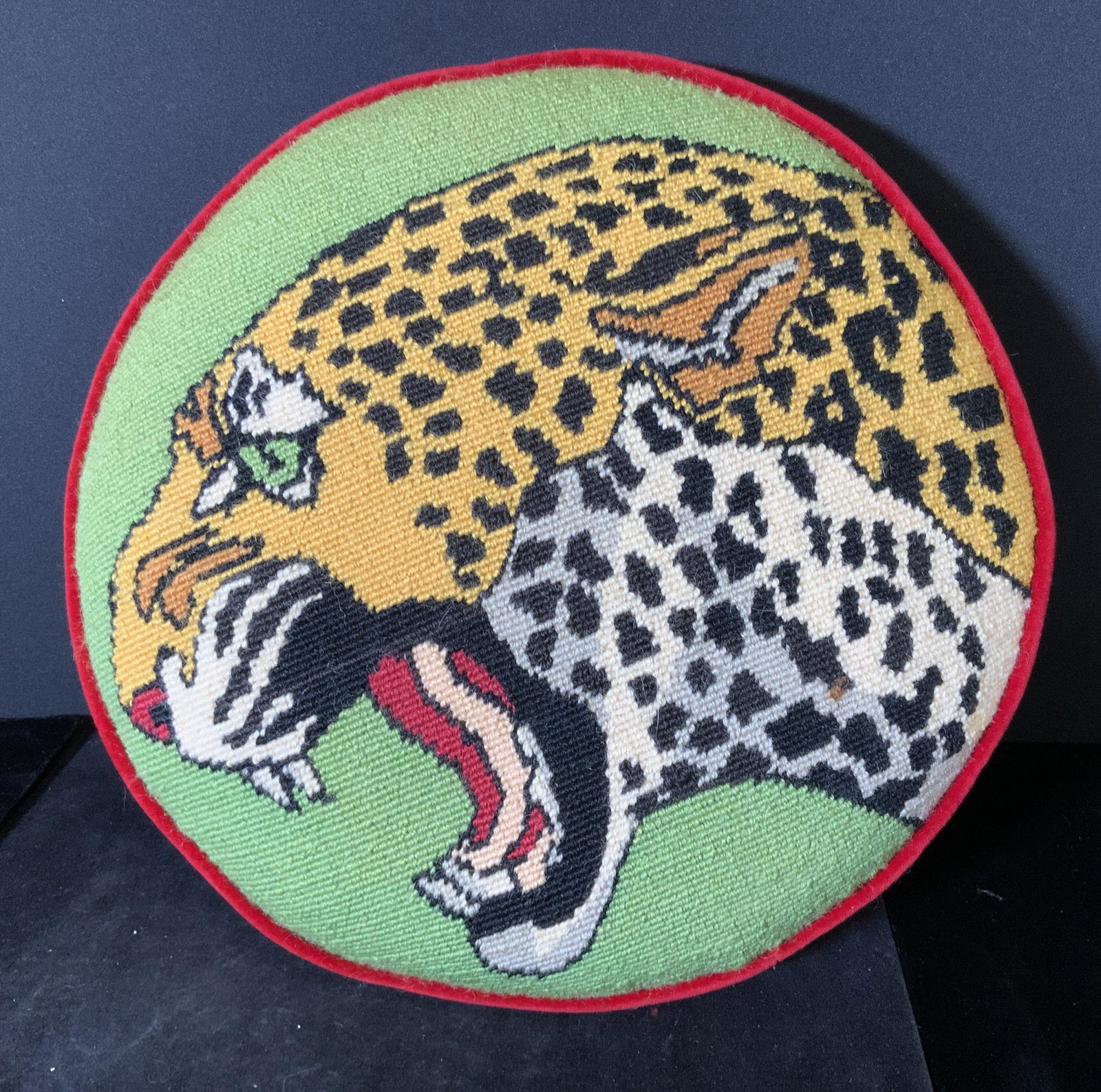NEEDLEPOINT LEOPARD Round Toss Pillow: Fierce LEOPARD head showing sharp teeth. Background grass green. Wool needlepoint pillow with red velour back, side and piping. Pillow form sewn in. 1 spot to wool thread can be spot cleaned, 12.5 in.