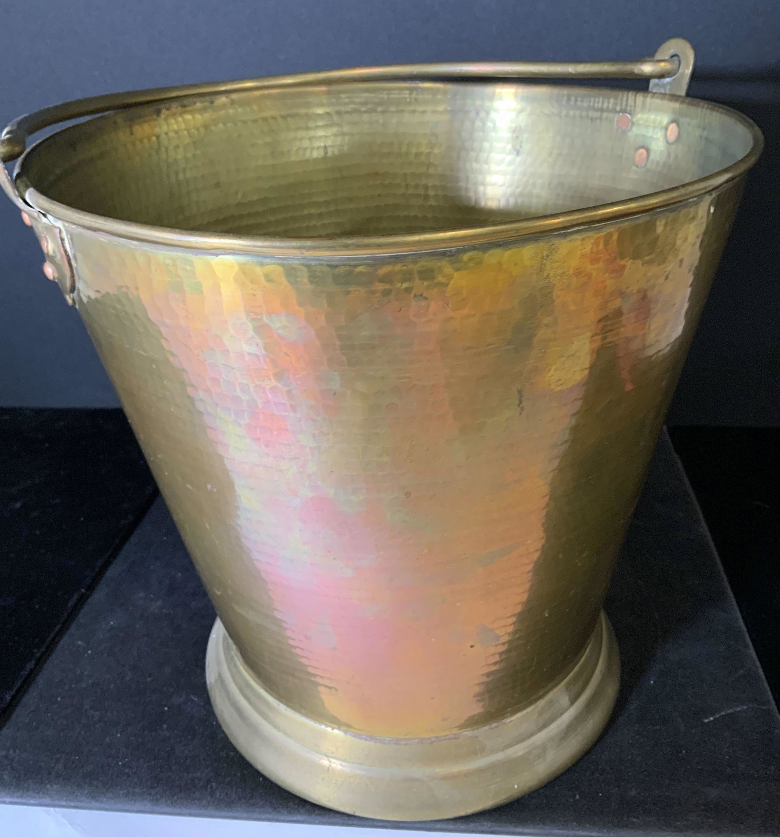 W.O.N.Y. 140/20 ANTIQUE HAMMERED BRASS BUCKET: Brass bucket with solid brass handle, swivels from end to end. Hammered metal pattern. Copper rivets. Underside reads India W.O.N.Y. 140/20, possibly Circa 1900. Medium weight. Ht 10.5 in. Diameter 10