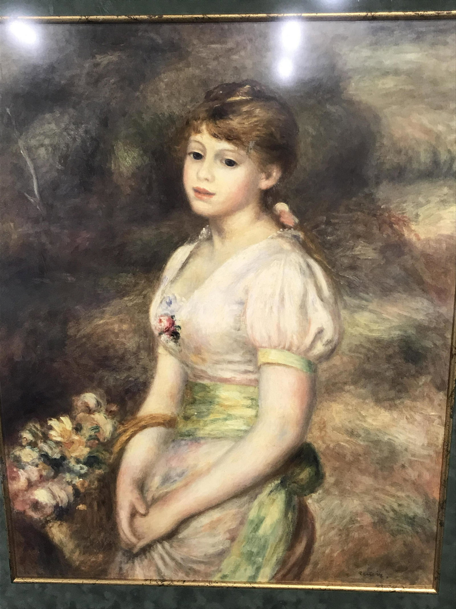 Print RENOIR’s Young Girl with a Basket of Flowers: Framed print of Pierre Auguste Renoir’s Young girl with a basket of flowers, signature printed to the lower right corner reads ‘Renoir’, subject a young girl in a pink and green dress holding a 