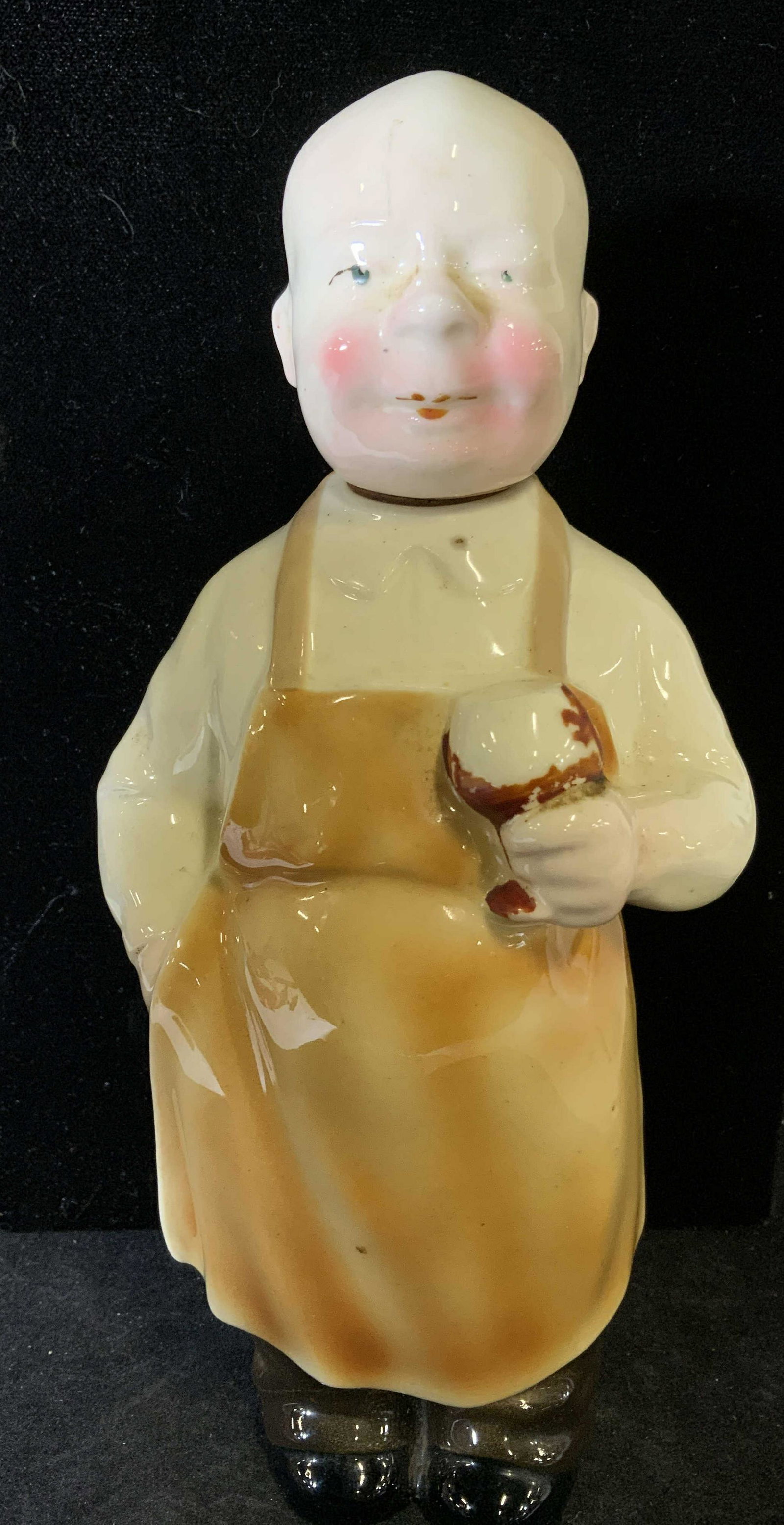 BOTTLE MAN WITH APRON Vntg Decanter, Germany: Vintage ceramic decanter bottle, bald man head decanter stopper with cork, bottle of man wearing apron hold a drink. Hallmarked Germany on verso. Bottle is 9 in. tall and about 4in. wide. Vintage Bald