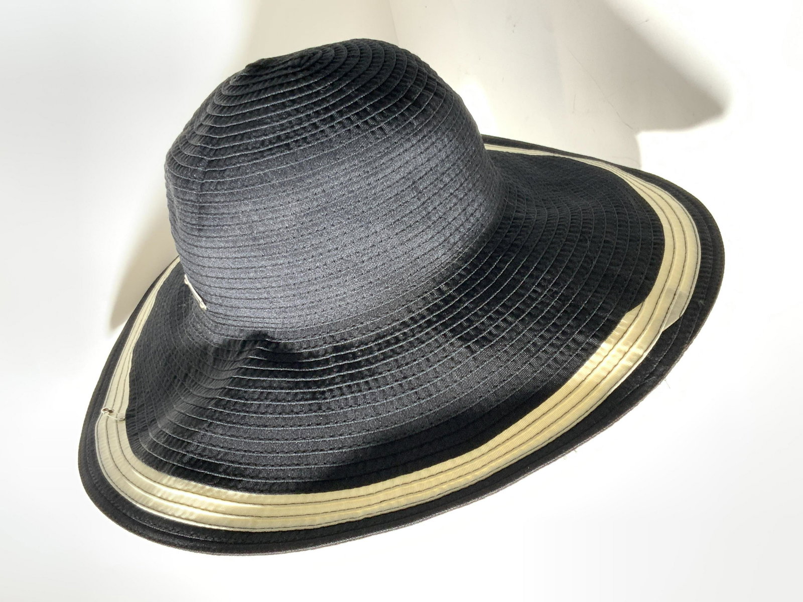 LAUREN by RALPH LAUREN Signed Black Fabric Sunhat: A black fabric sunhat created by Ralph Lauren. The hat has a white trim along the brim of the hat, The green interior tag on the hat reads : Lauren, Ralph Lauren. M. Made in China. RN 26128. Size: Med