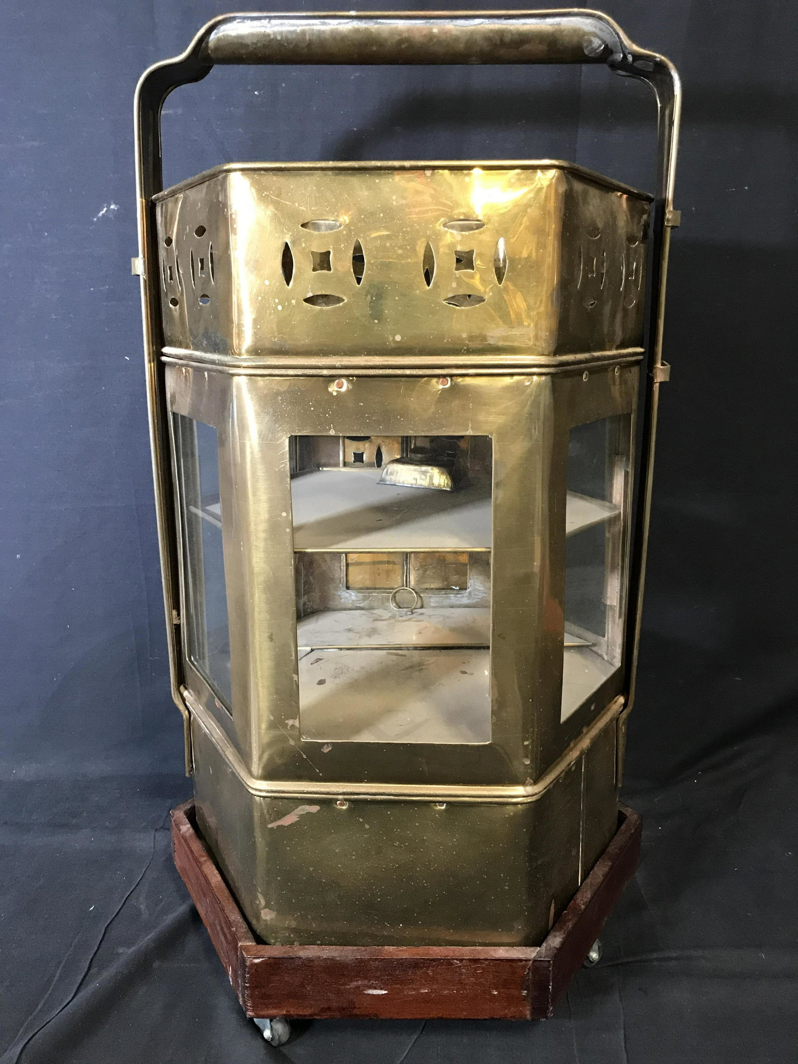 Upcycle Brass Octagonal Shelf/Bar Cart: Upcycle brass octagonal shelf/bar cart, piece is made almost entirely out of brass with glass windows to the sides and a door with latch to the front, piece includes a wooden base with wheels, inside 
