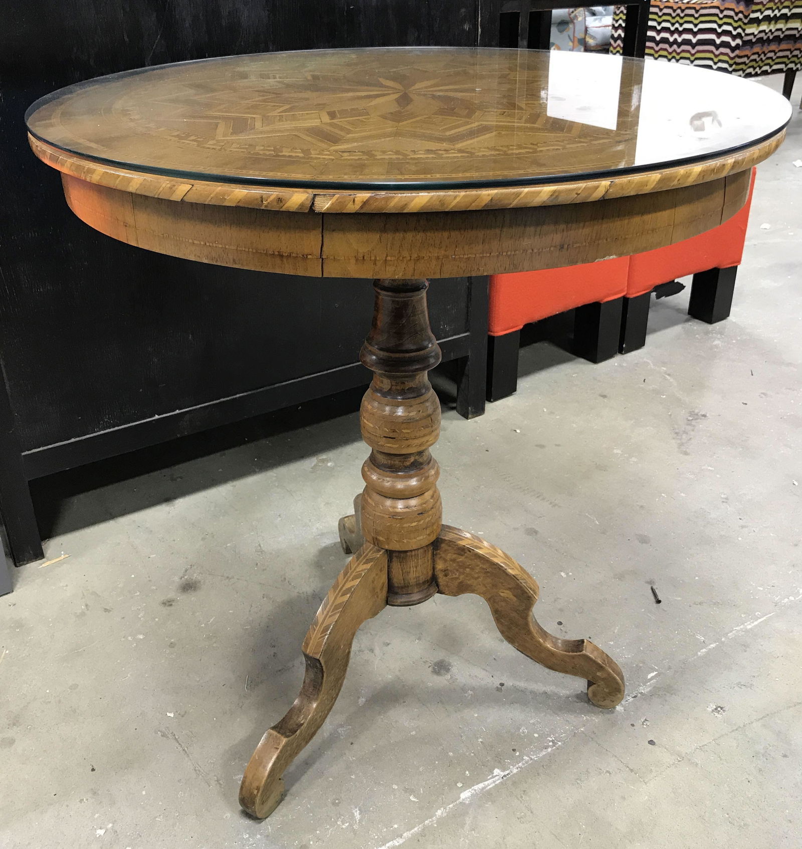 Wooden Mosaic Table with Glass Top: Wooden Mosaic table with glass top, no apparent stamps or labels, some chips and wear to piece, three legged table, diameter of table measures at 27 inches, table measures 29 at tallest point, Wooden