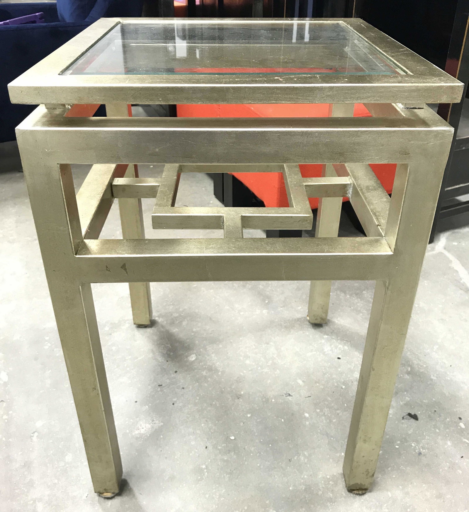 Industrial Modern Metal Glass Top Side Table: Side table is gold toned and metal. Piece has Beveled glass top. Piece has industrial modern style. Piece measures approximately 27 inches tall 18 inches wide and deep. Side table, end table, lamp tab