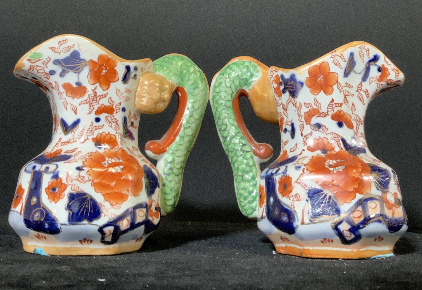 Pair Signed Antique Asian Imari IRONSTONE Pitchers: Pair of antique Asian Imari ironstone pitchers with snake handles. The colors include saffron, cobalt, white, and green hues. Gilt accents throughout pieces. The snake handles are green with embossed 