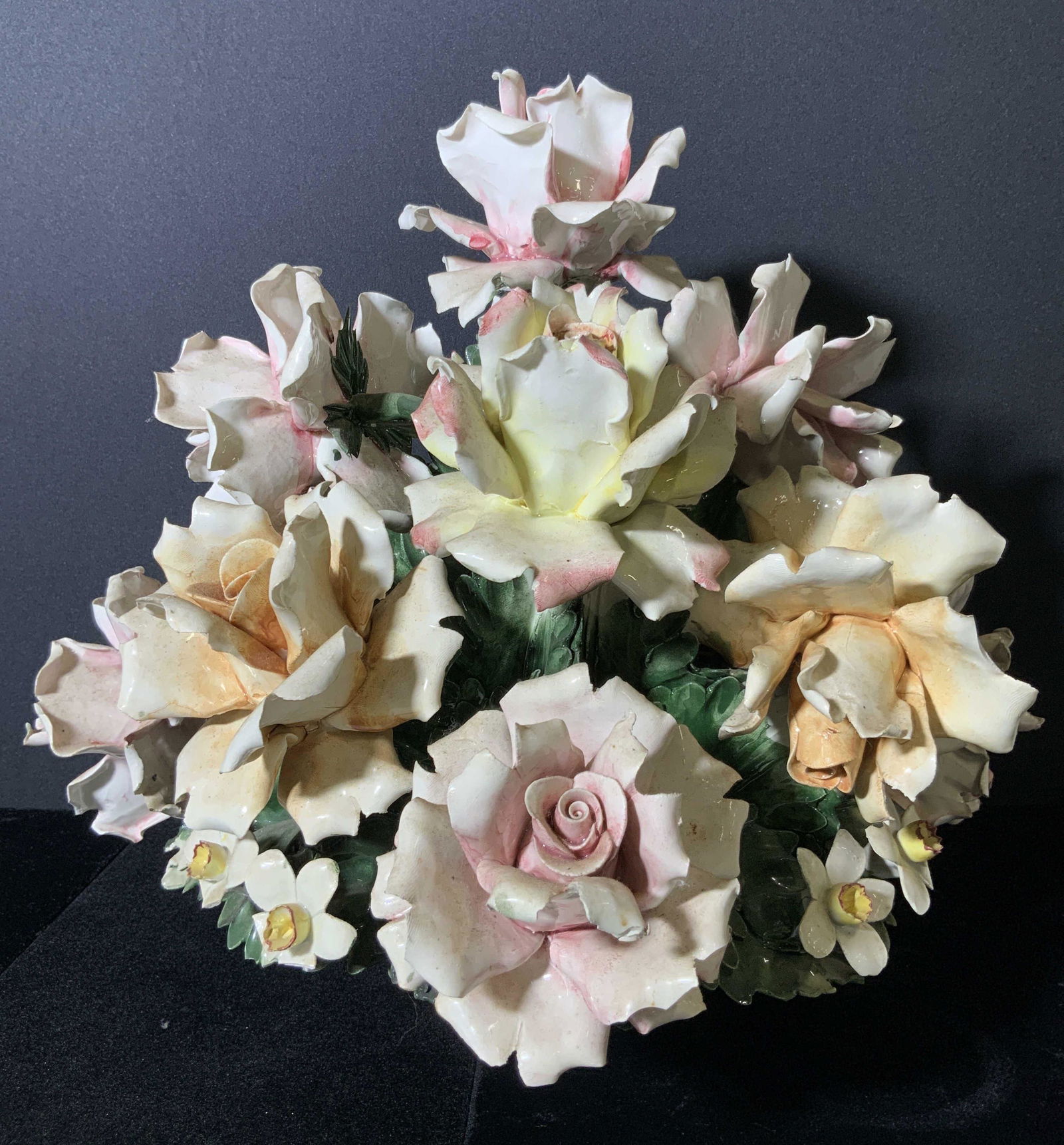 Signed CAPODIMONTE Antique Toleware Centerpiece: Antique Toleware and porcelain floral centerpiece. The basket which holds the flowers is hand painted in brown hues. Embossed porcelain makes the basket look as if it has been woven. The Toleware flow