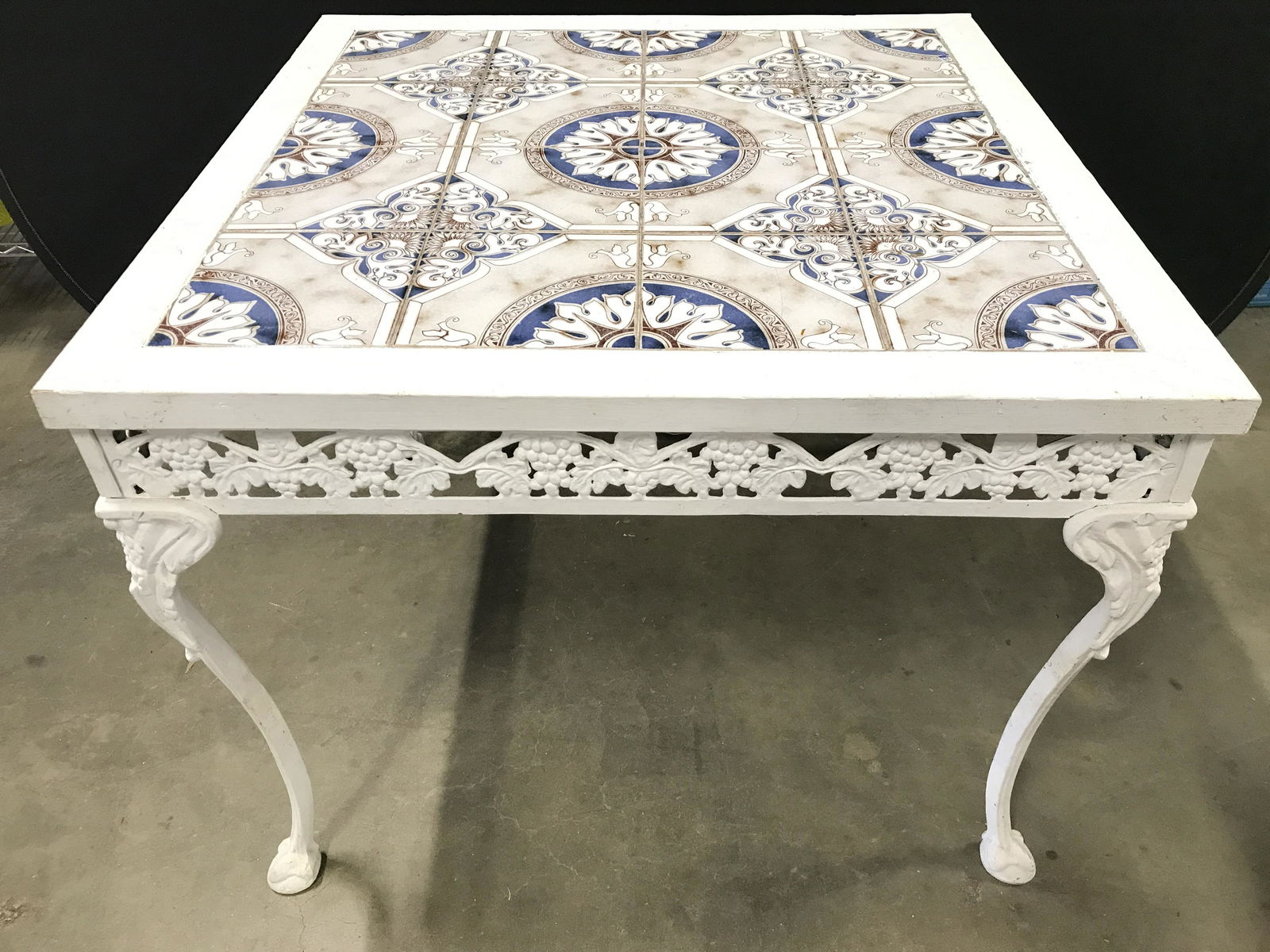 Vintage Tiled Metal & Wooden Patio Table: Table is vintage possibly antique. Piece has tile top with multi toned geometric detail in a cohesive pattern design. Piece has metal legs with floral, leaf, grape & vine detail. Piece measures approx