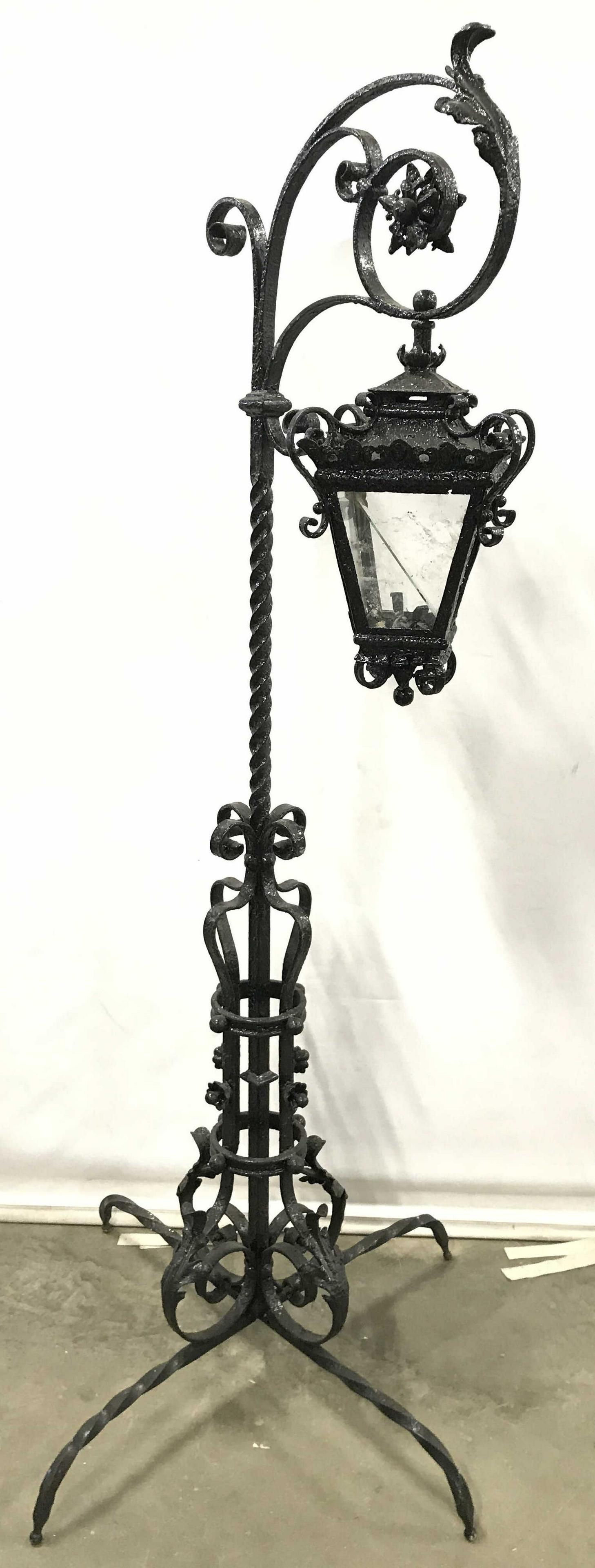 Antique Outdoor Victorian Metal Floor Lamp: Lamp is antique. Piece has Victorian stylings. Contains floral & leaf structures in addition to c and s curve detail. Would be lit Area dangles and has 4 glass panes. Piece has 4 low leg supports maki