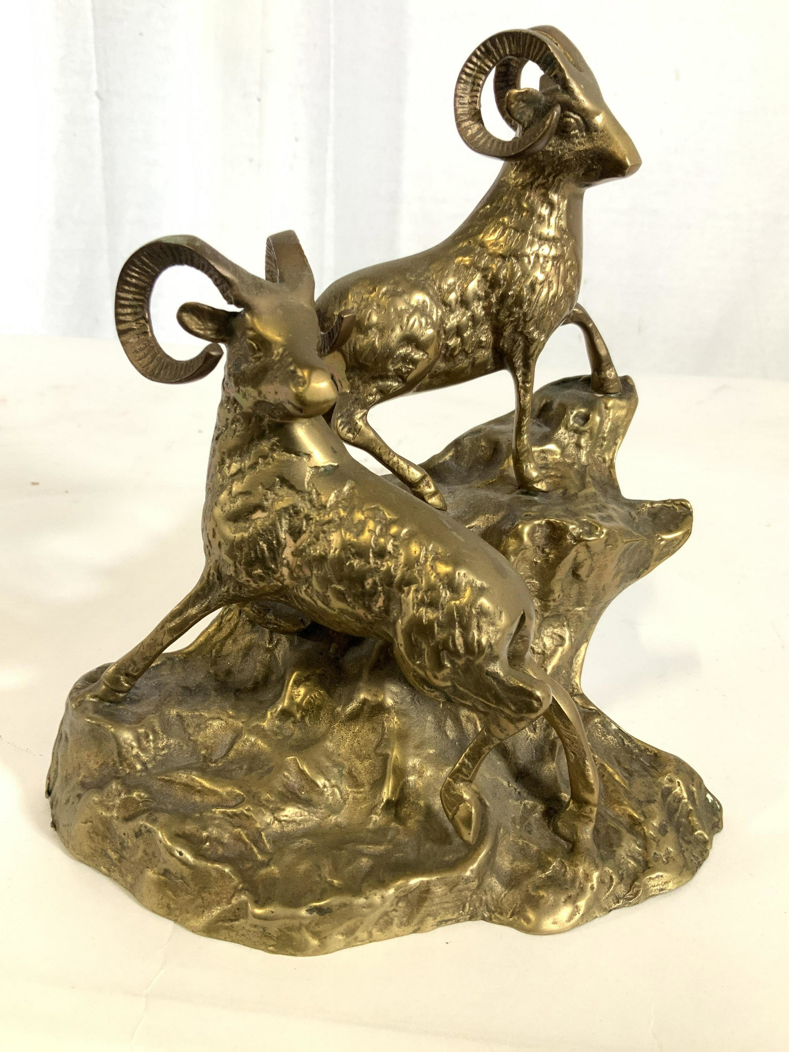 Brass Rams On Hillside Sculpture: Sculpture is brass, gold toned metal, scene of two rams with curled horns standing on cliff mountain side, desk accessory, decorative arts, decorative accessory, animal statuary, animal art, apparentl