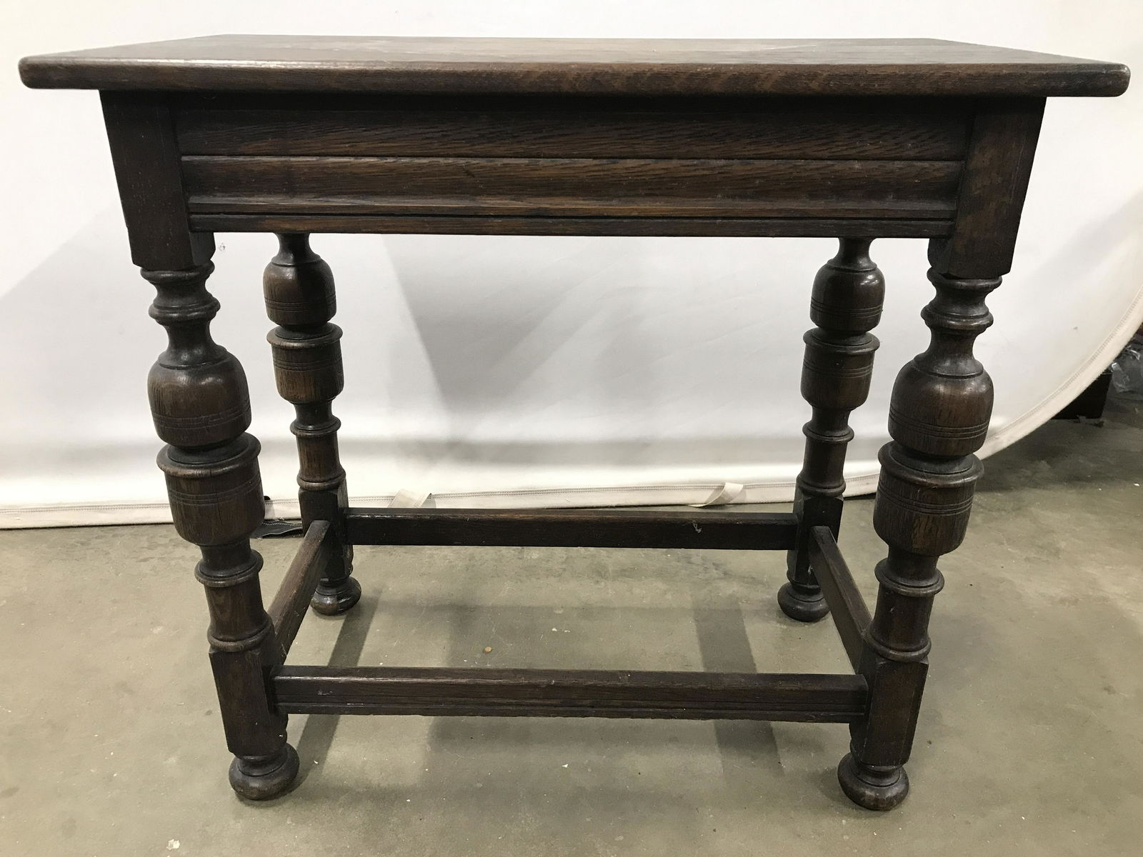 Antique Carved Wooden Side Table: Side table is vintage possibly antique. Piece is brown toned & wooden. Piece is possibly hand crafted. Legs have stretchers in between. Piece measures approximately 26 inches tall 24 inches long 13 in