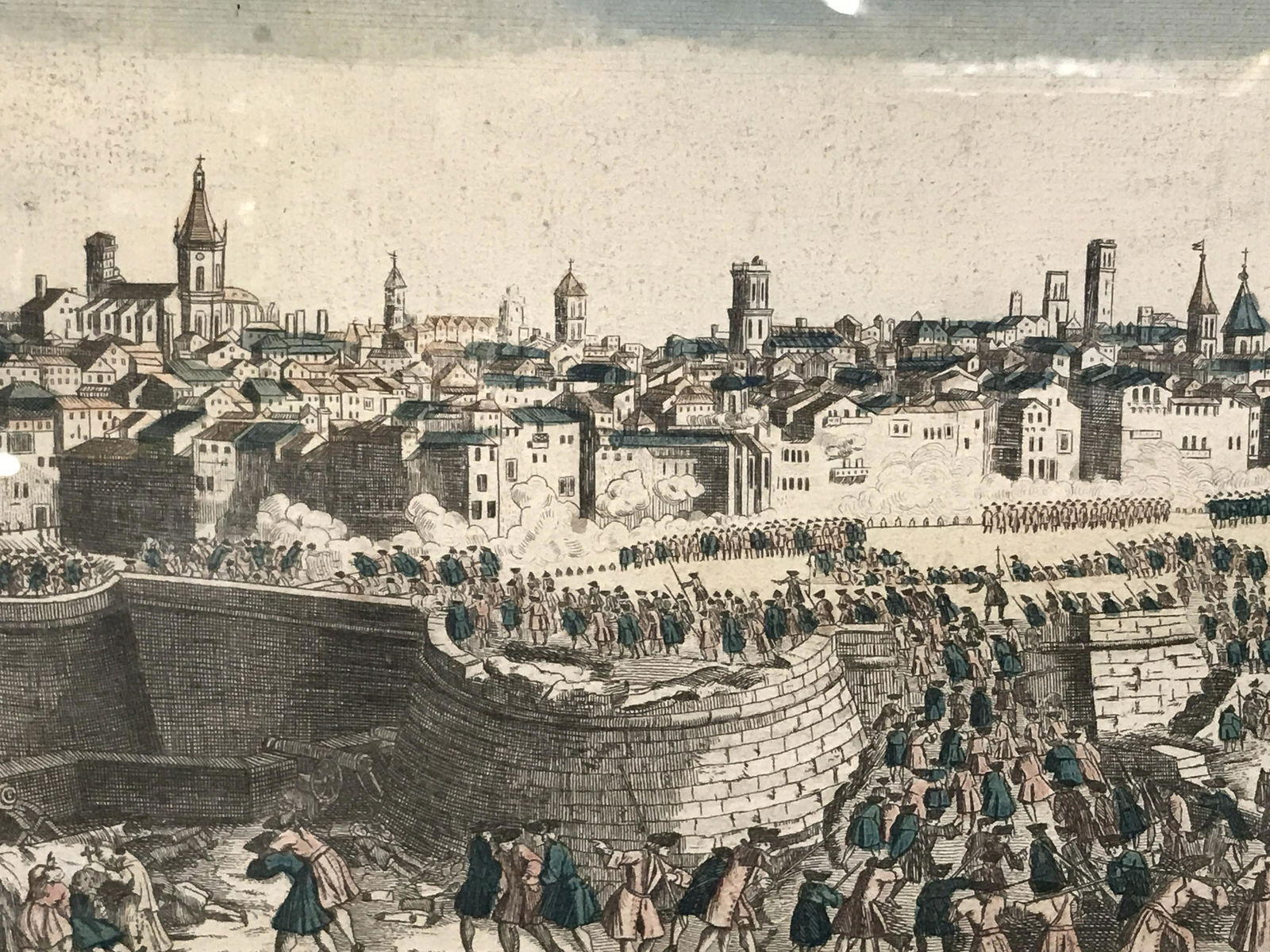 Hand Colored French Battle Scene Engraving Art: Hand colored French Battle Scene Engraving, text to lower bored in French, subject a battle scene spanning over a city of brick, no apparent signatures or stamps, grey wooden frame, measures 9.25 inch