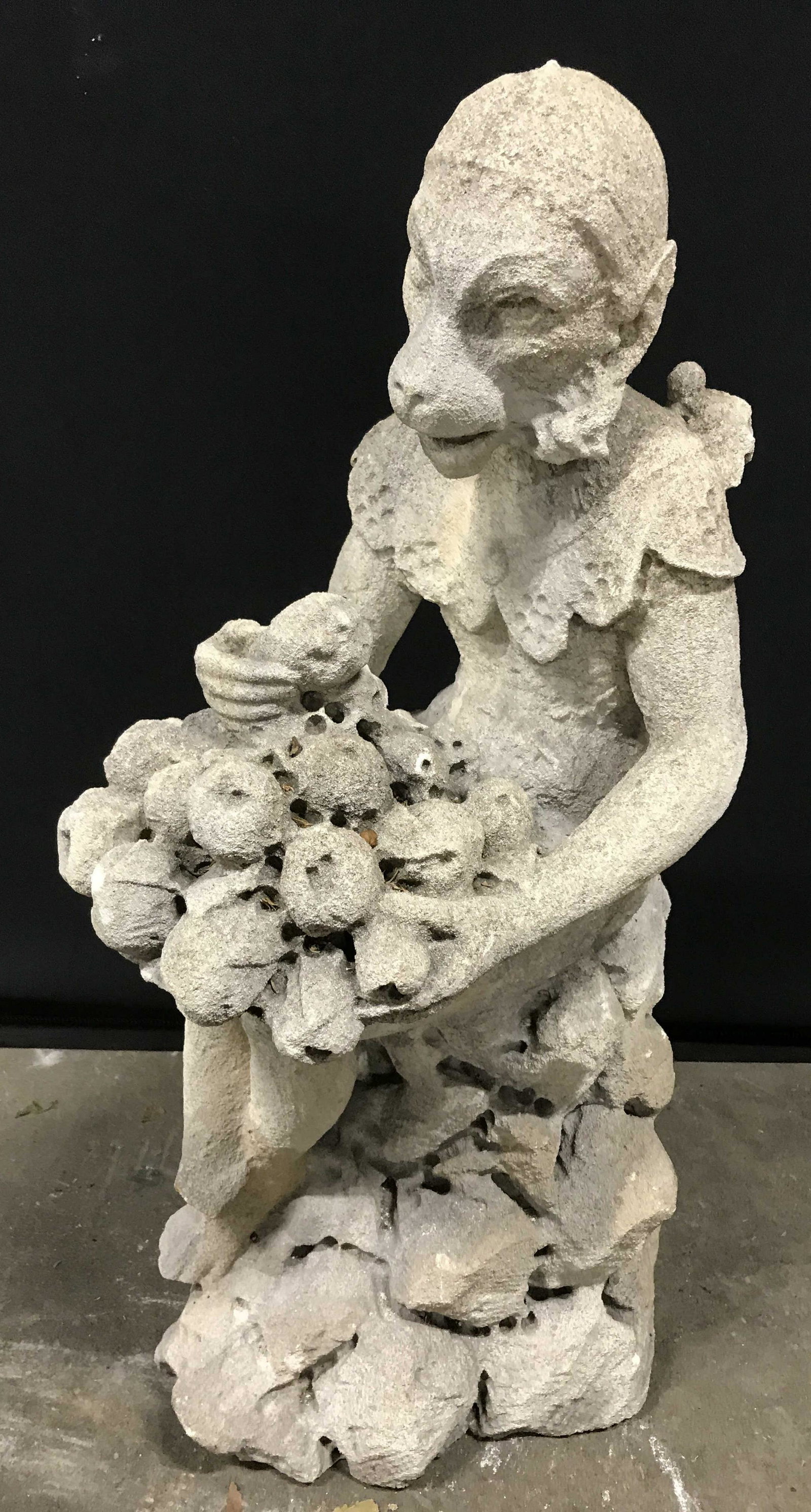 Vintage Stone Monkey Garden Statue 26 in H: Vintage stone monkey sculpture, possibly cement. Depicts a monkey, wearing a dress, eating fruit, sitting atop rocks. Measures approx 26 inches H, and 13 inches W. Wear is consistent with age and expo